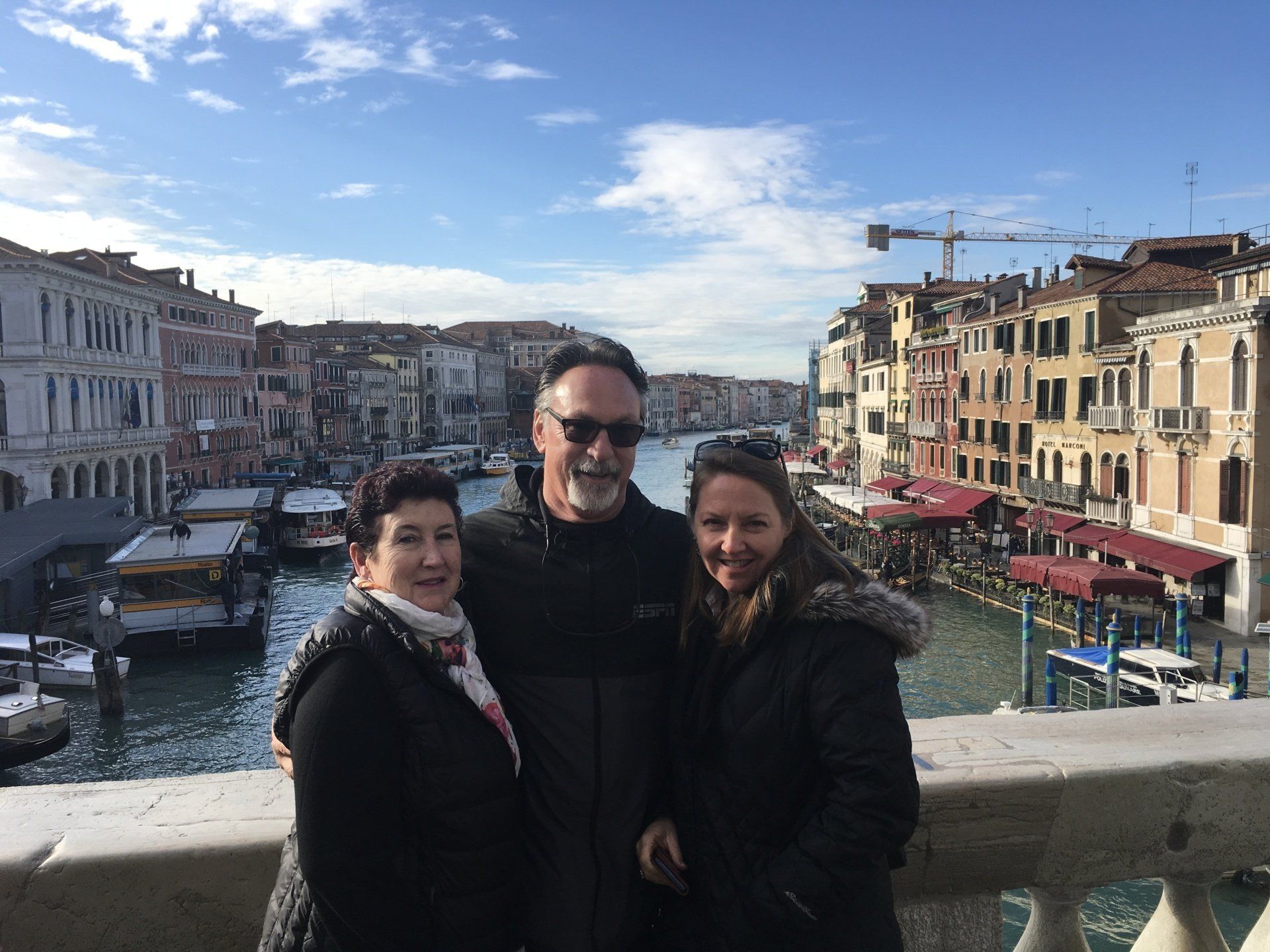 A man and two women are posing for a picture on a bridge over a river.