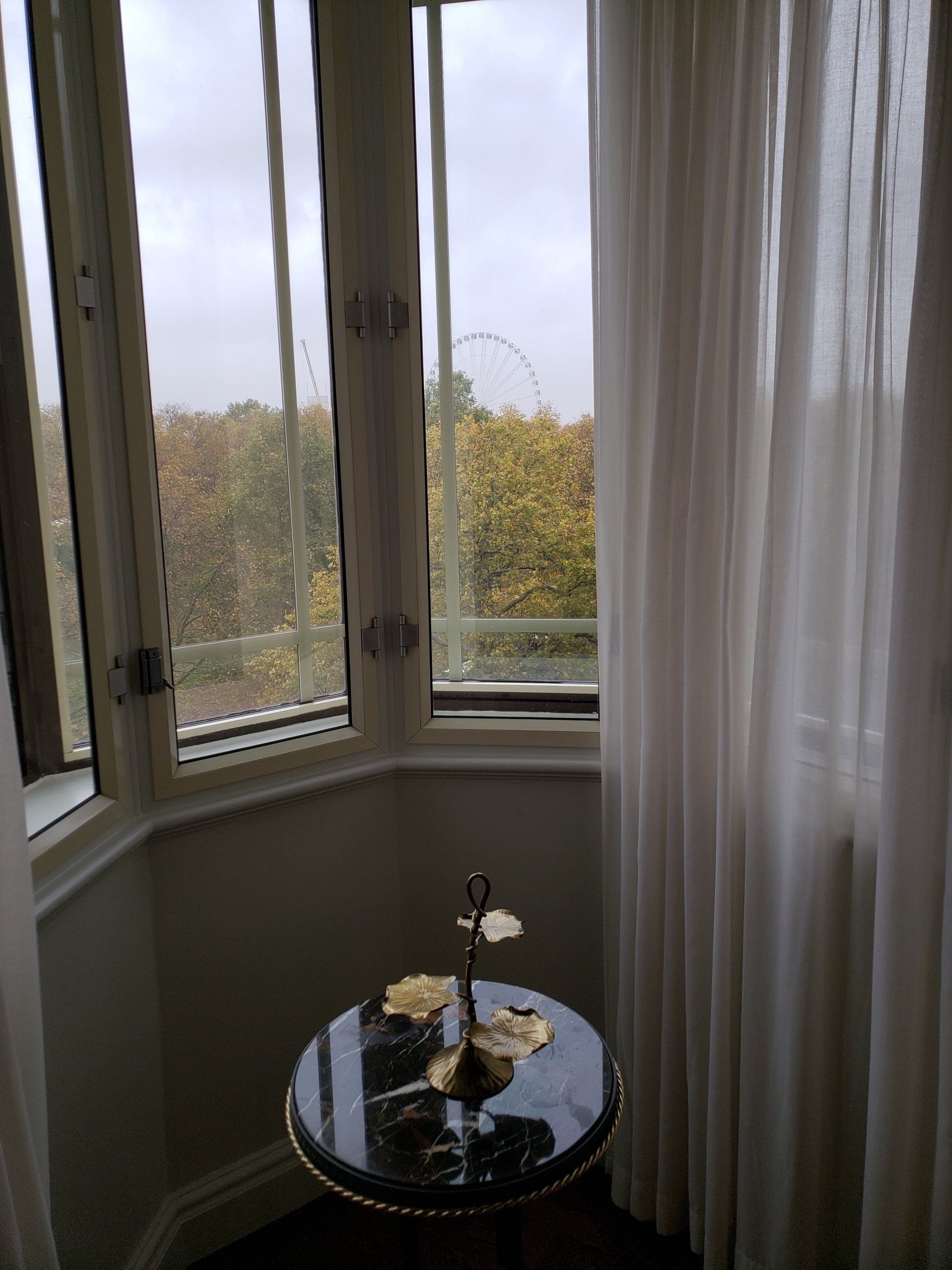 A small table in front of a window with white curtains.