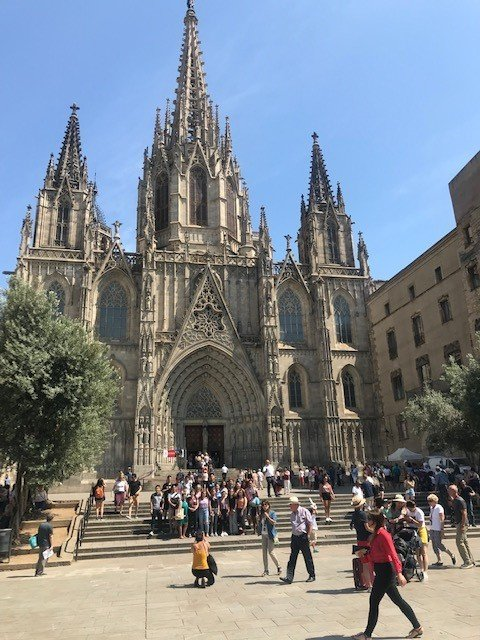 A group of people are walking in front of a large cathedral