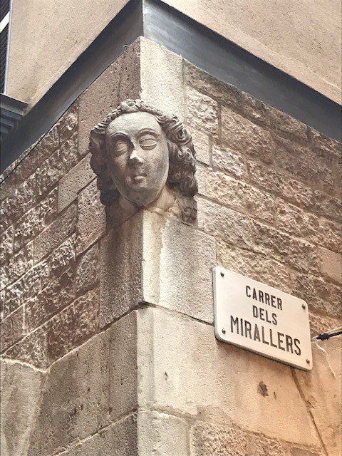 A statue on the corner of a building with a sign that says carrer dels mirallers