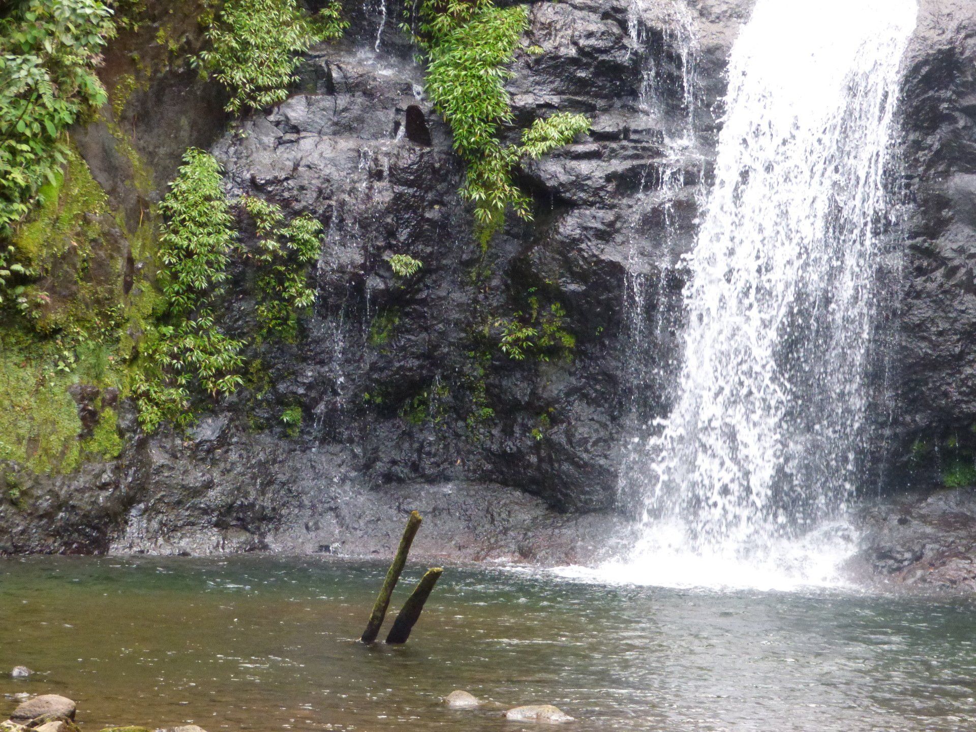 A waterfall is surrounded by rocks and trees and is surrounded by a body of water.