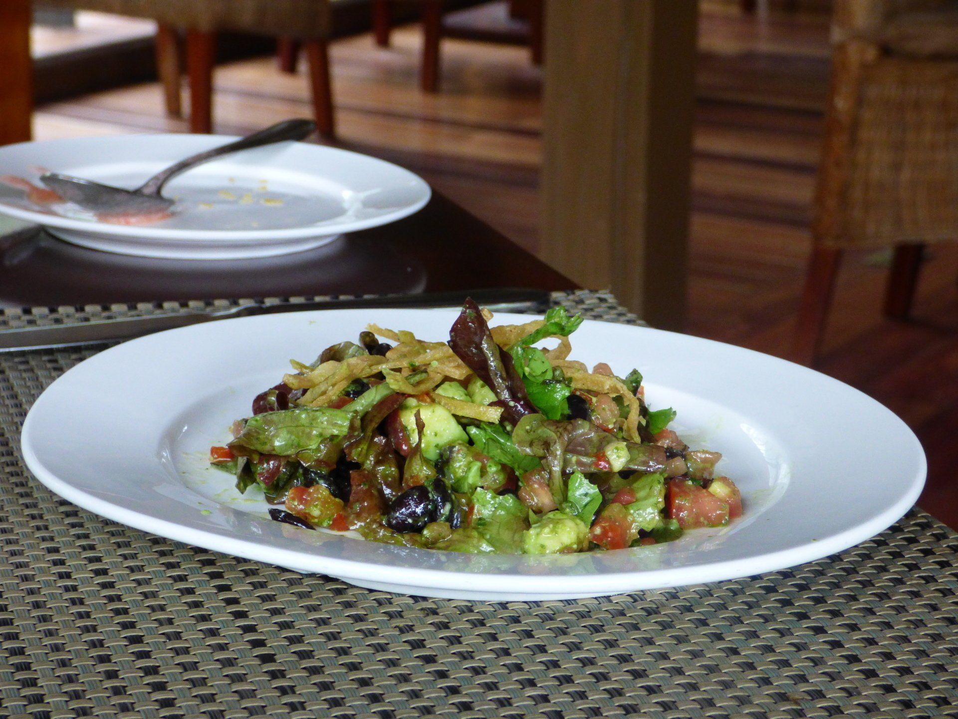 A white plate with a salad on it on a table