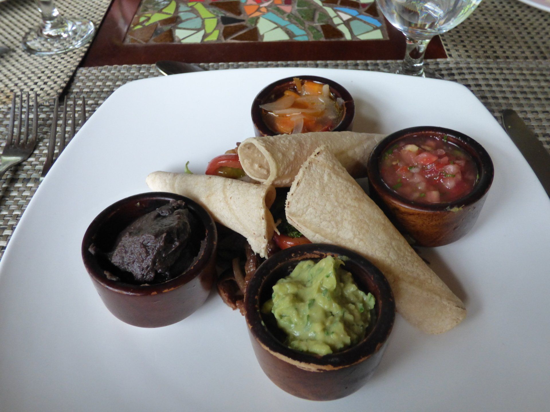 A plate of food with guacamole black beans and salsa