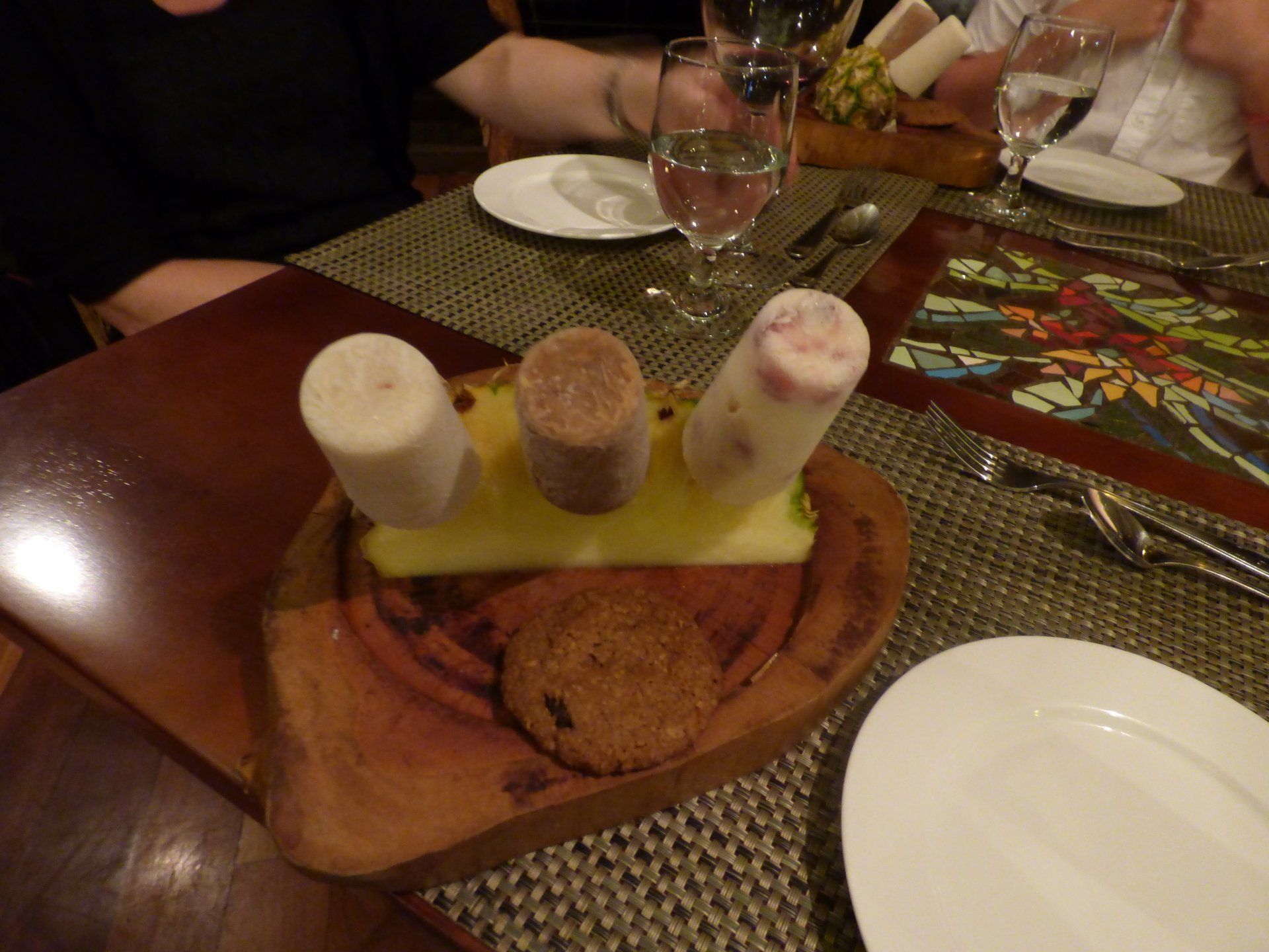 A wooden tray of food on a table with plates and silverware
