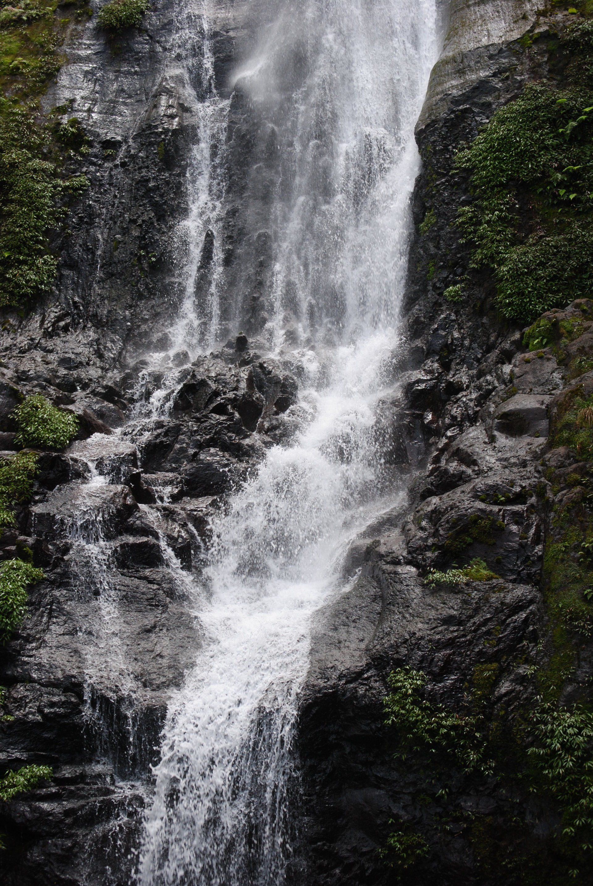 A waterfall is coming down a rocky cliff surrounded by trees.