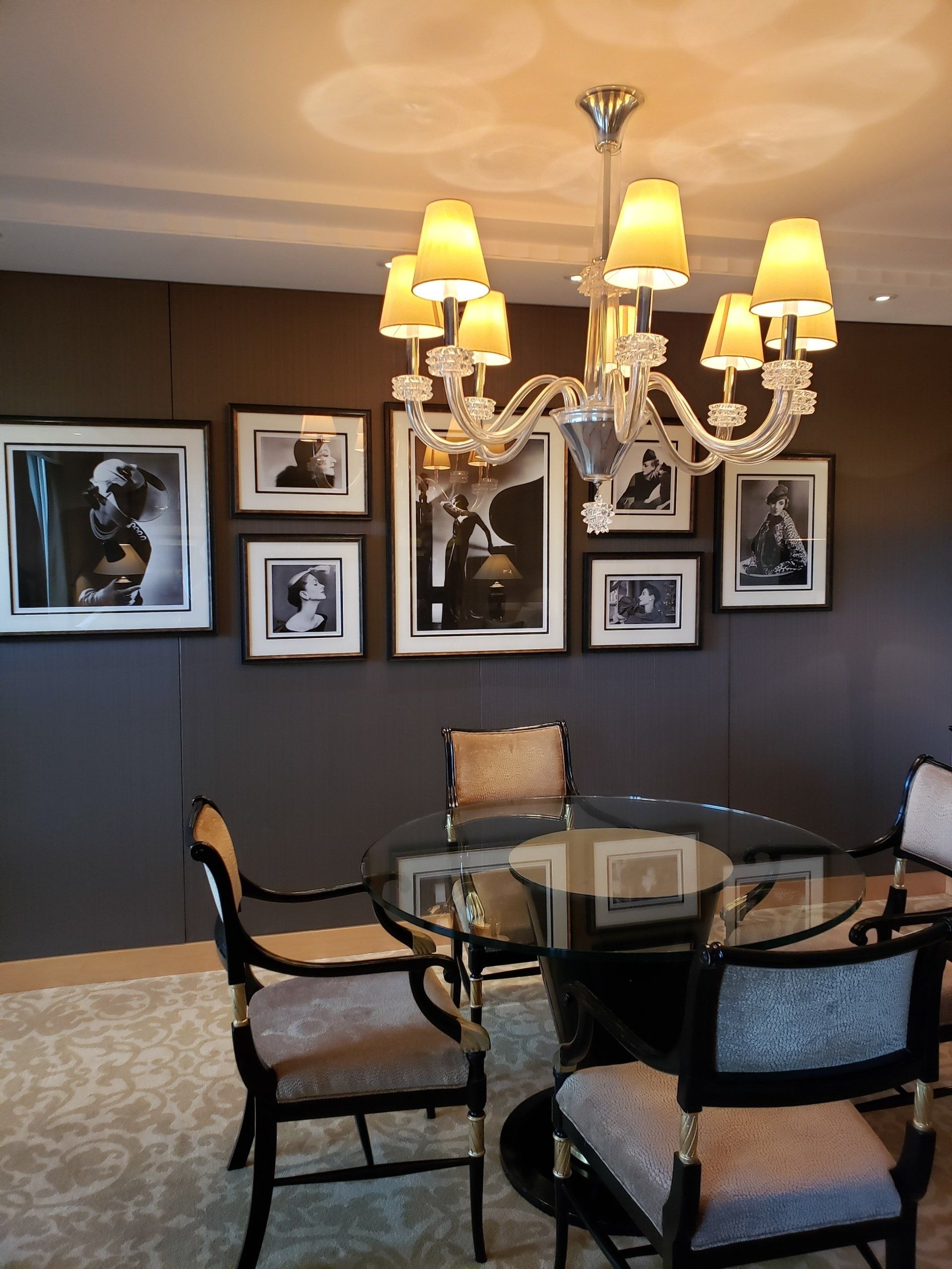 A dining room with a glass table and chairs and a chandelier