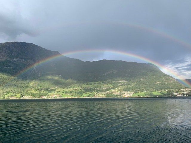 A rainbow over a lake with mountains in the background.