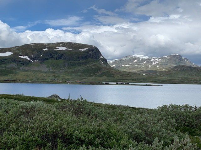 A lake with mountains in the background and trees in the foreground