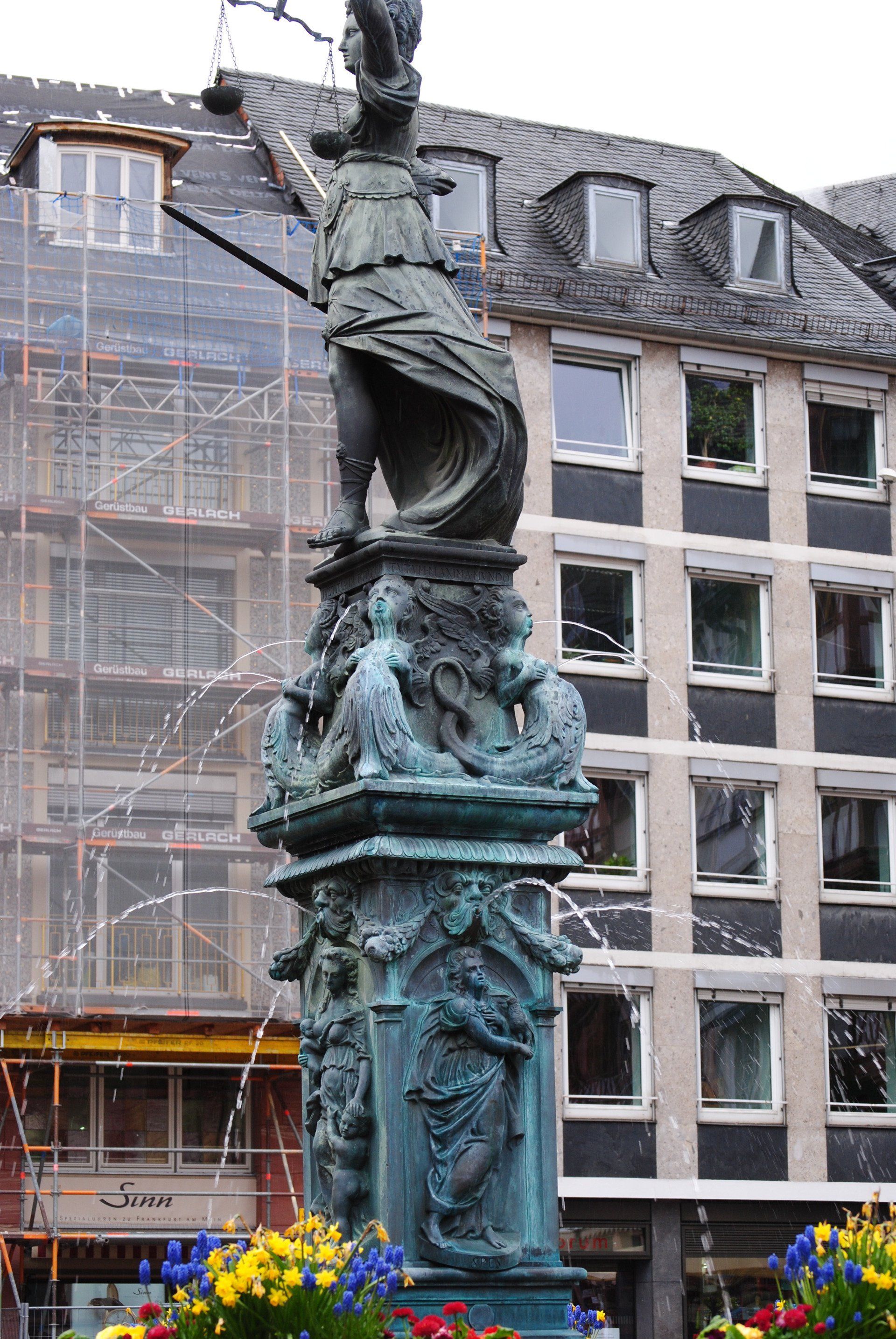 A statue in front of a building with flowers in front of it