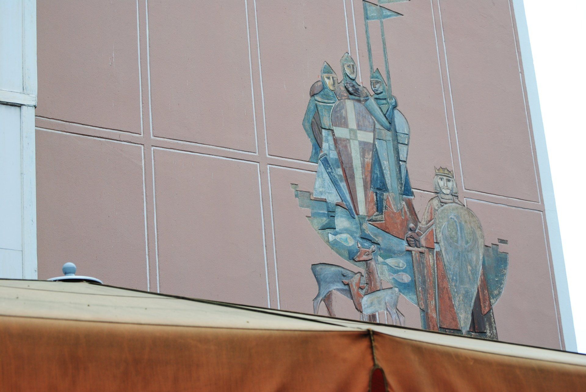 A painting on the side of a building shows a man holding a flag