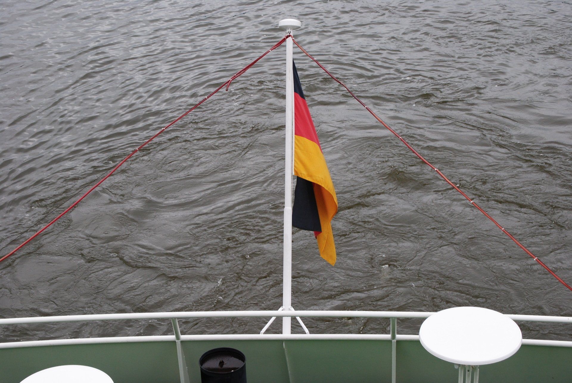 A german flag is flying on the back of a boat