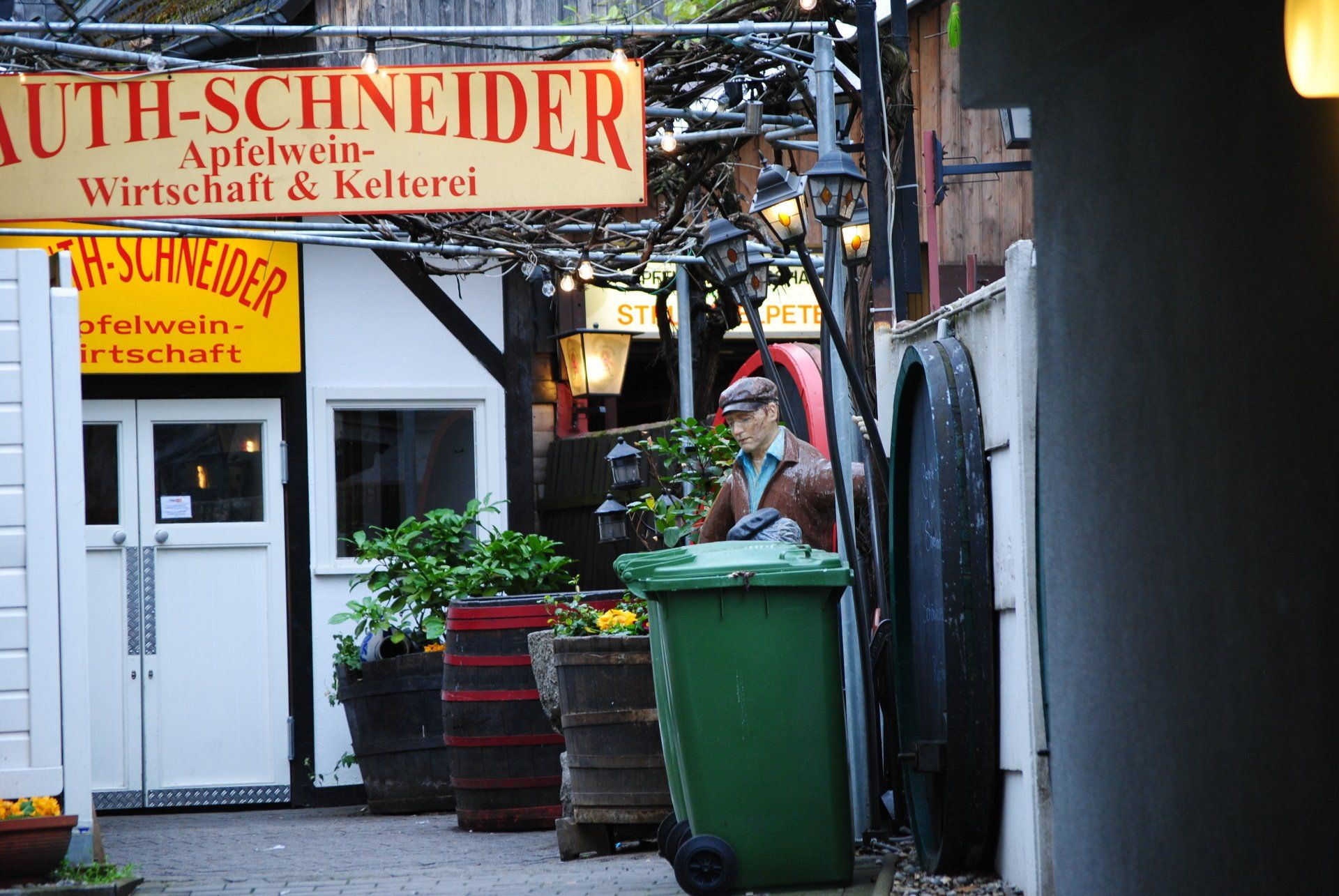 A green trash can is in front of a sign that says auth-schneider