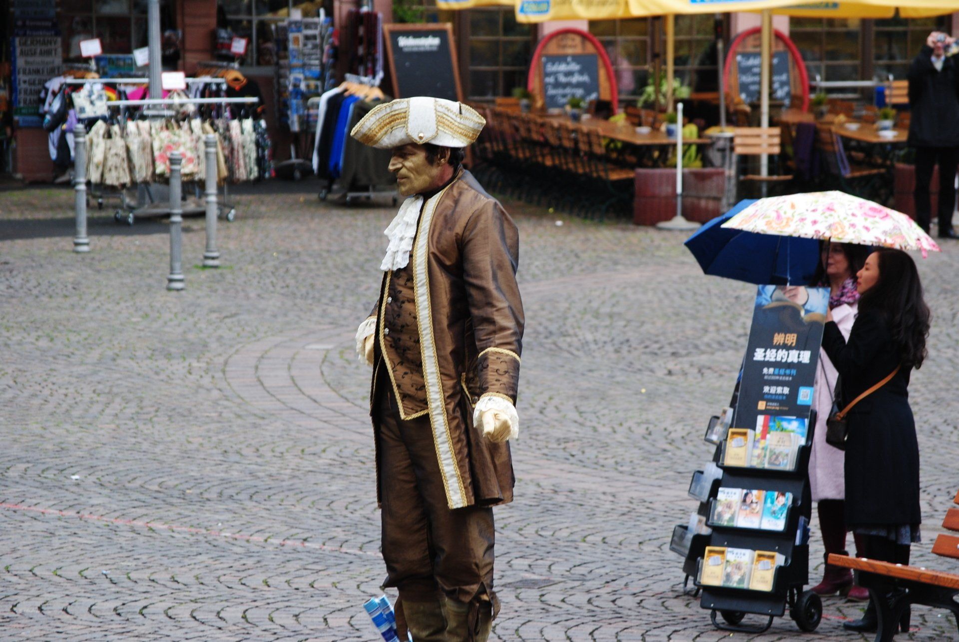 A man in a costume is standing next to a woman holding an umbrella