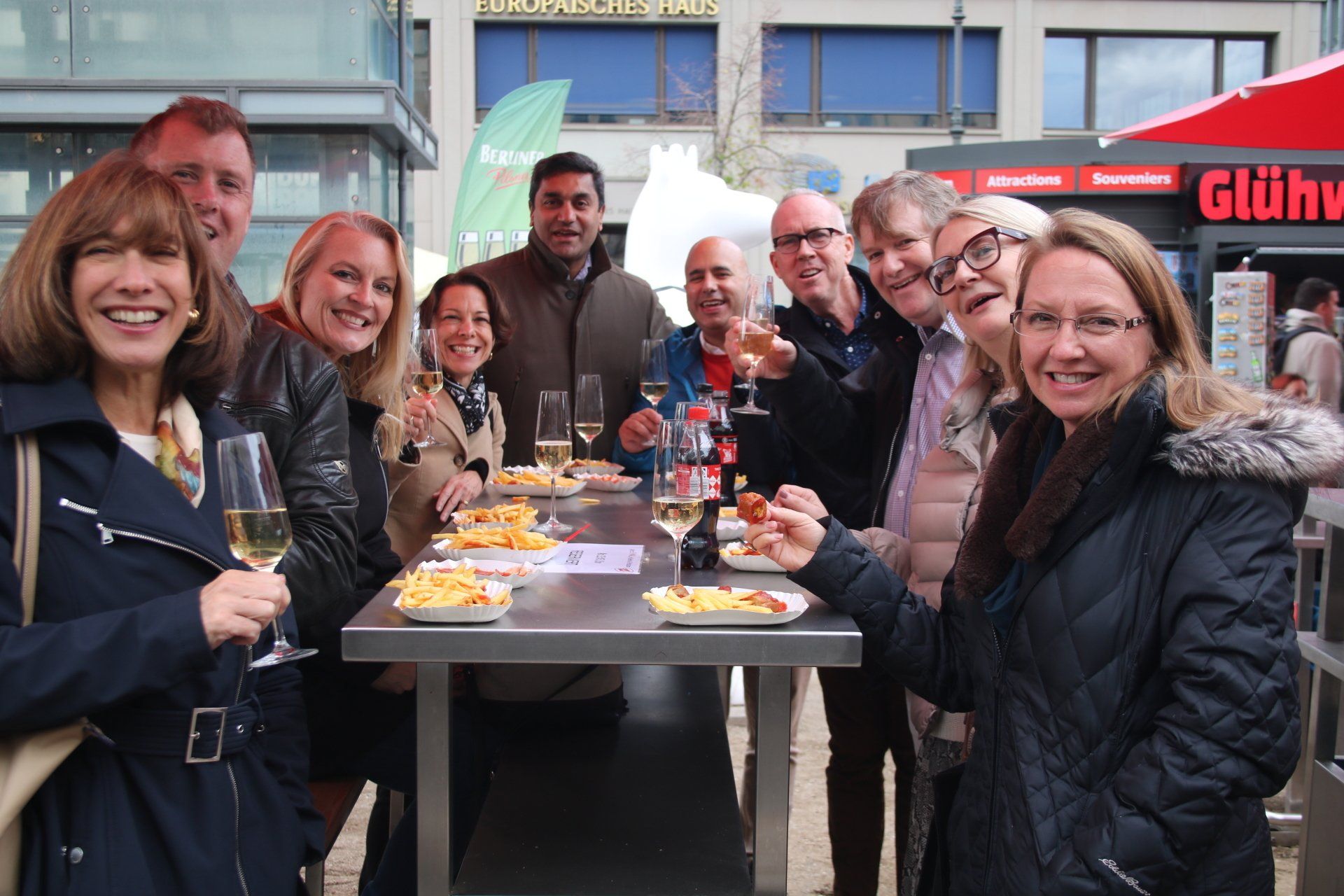 A group of people are standing around a table holding glasses of wine.