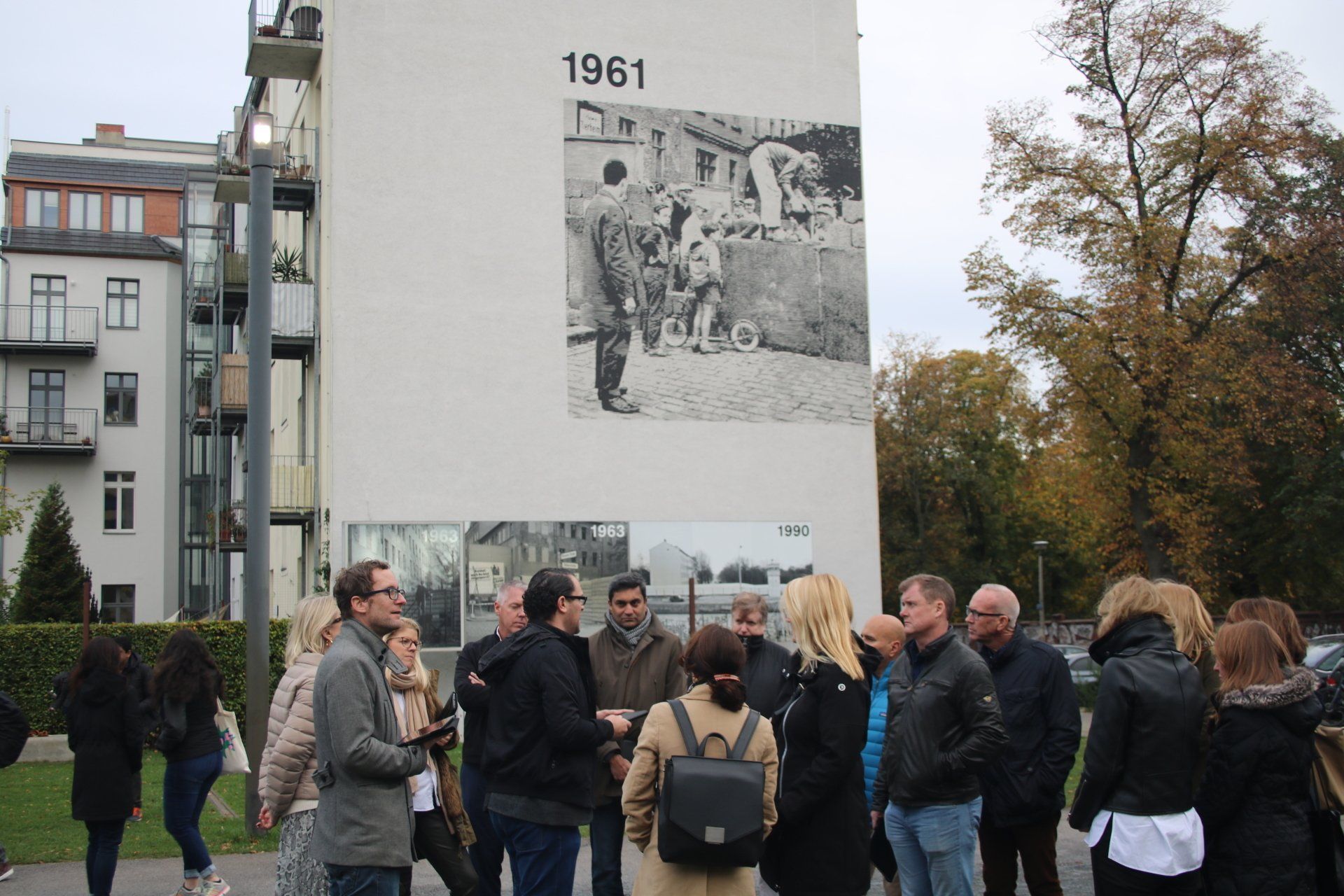 A group of people standing in front of a wall that says 1961