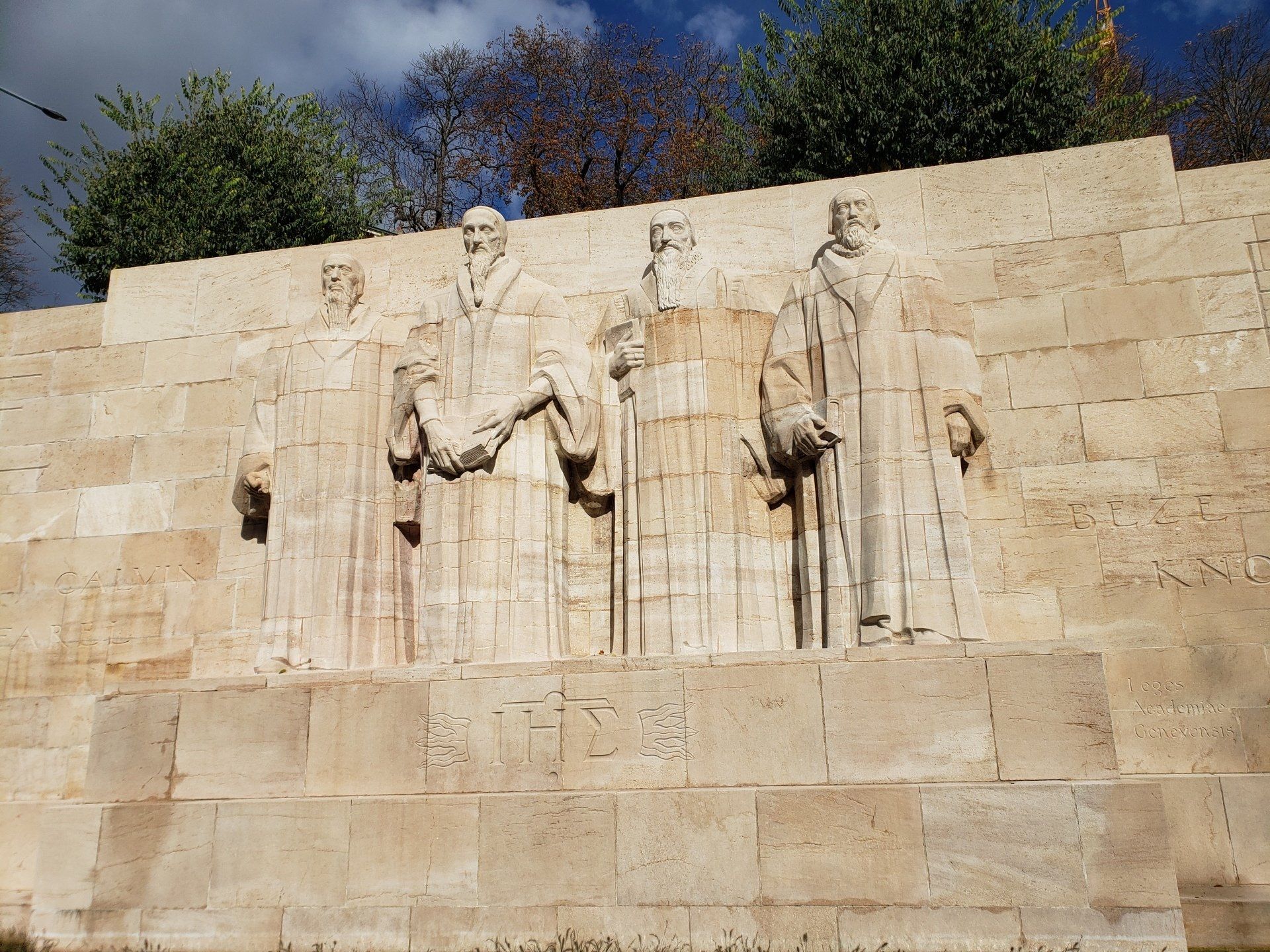 A stone wall with a statue of three people on it