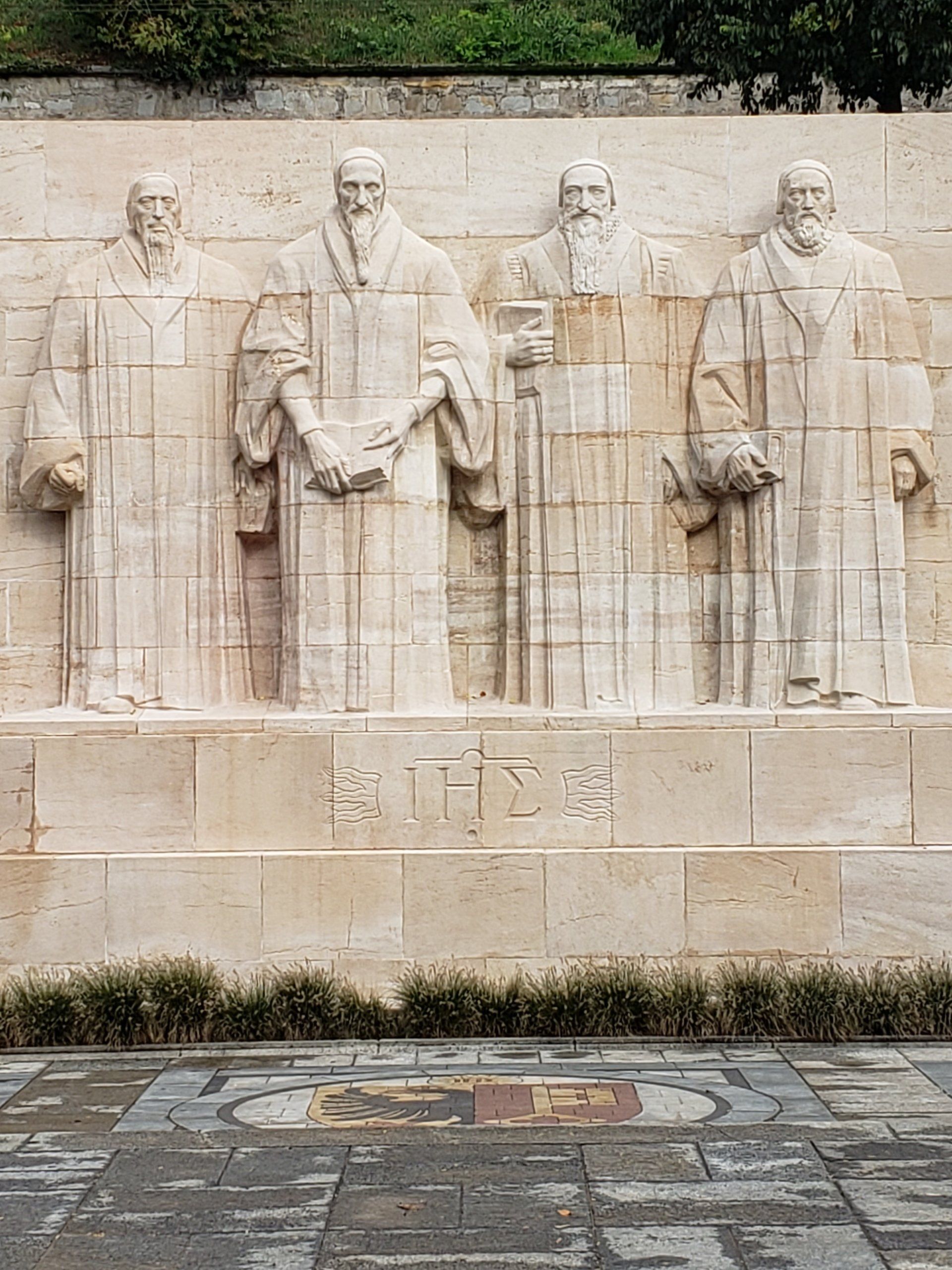 A statue of four men standing next to each other on a wall.