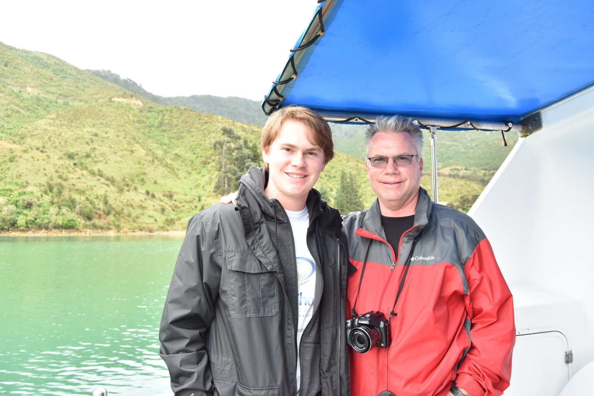 Two men are posing for a picture on a boat.