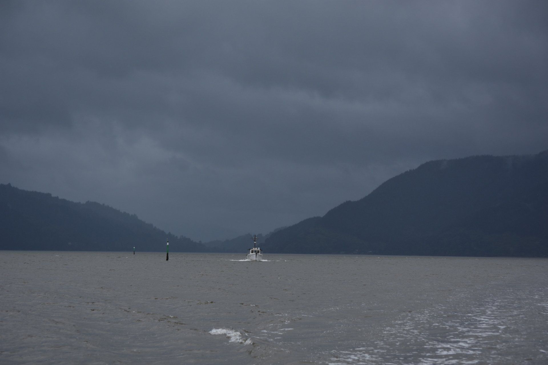A boat is floating on a lake on a cloudy day.