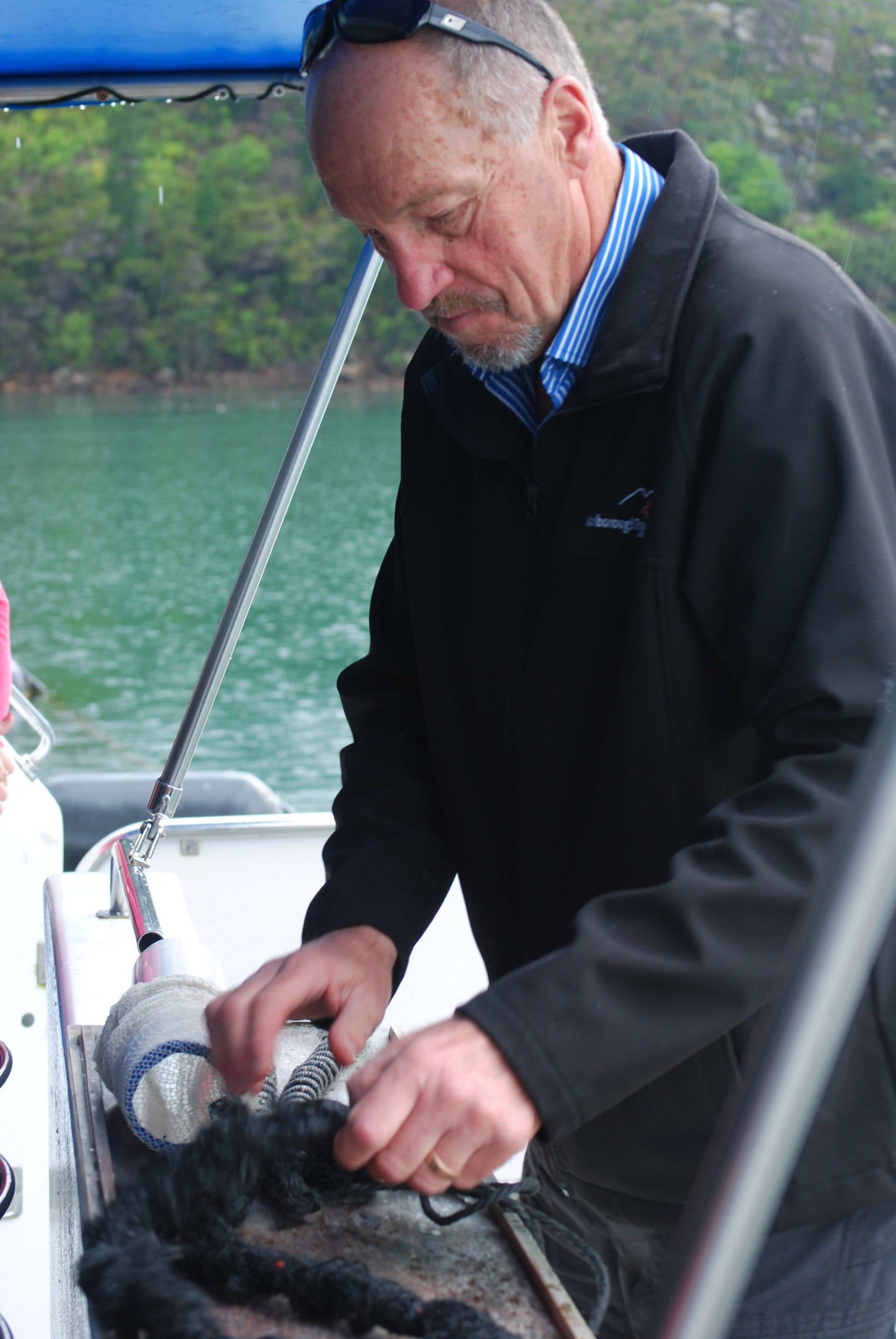 A man in a black jacket is working on a boat