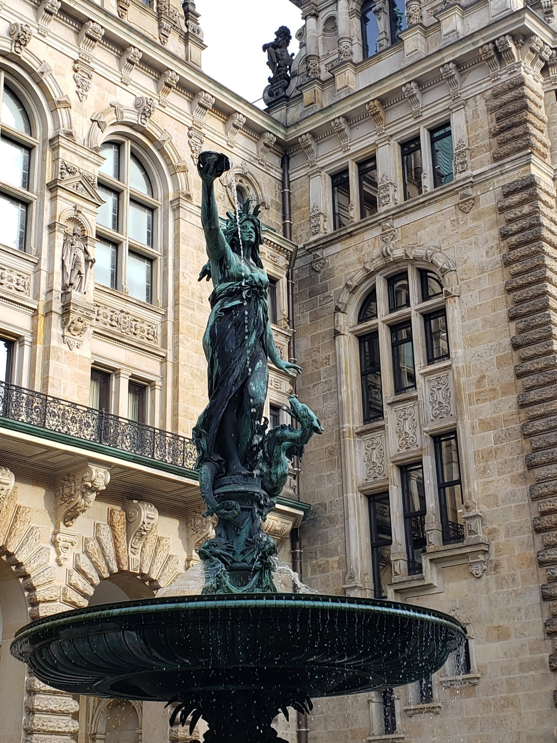 A fountain with a statue of a woman in front of a building