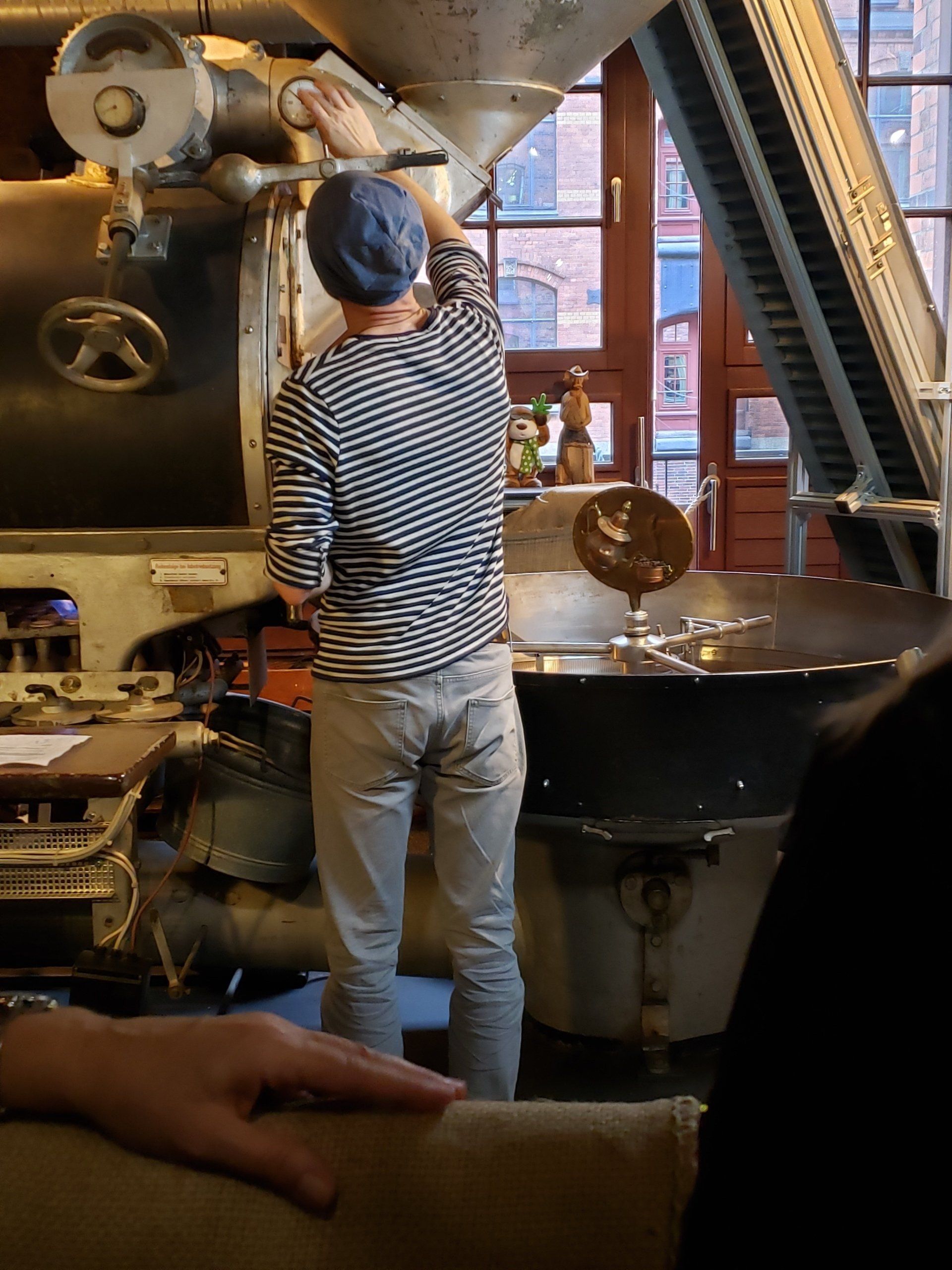A man in a striped shirt is standing in front of a machine