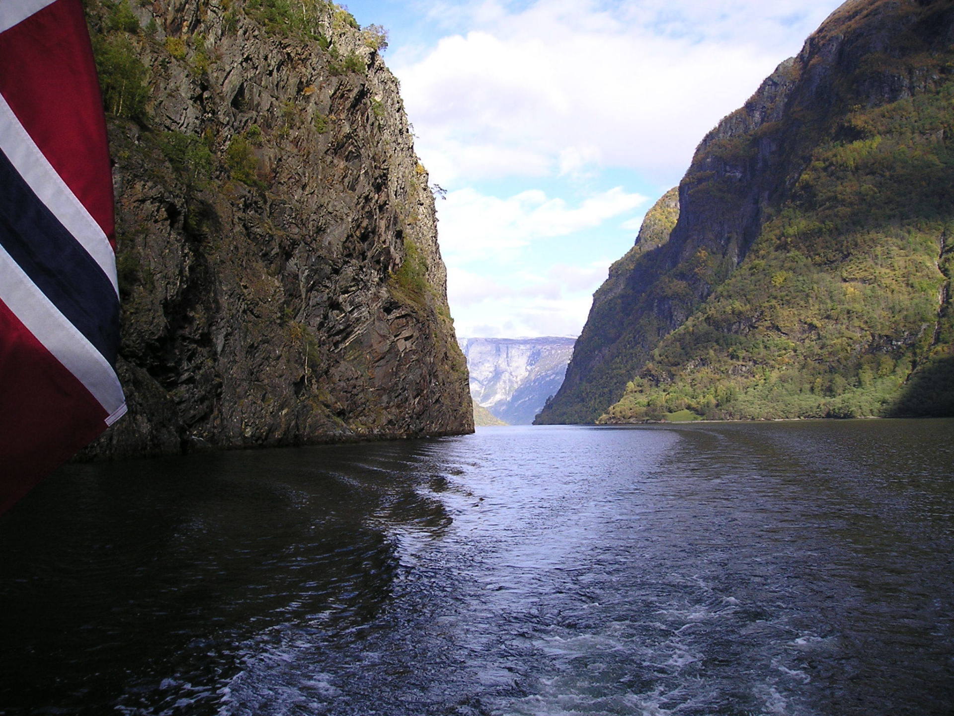 A boat is going through a canyon with mountains in the background