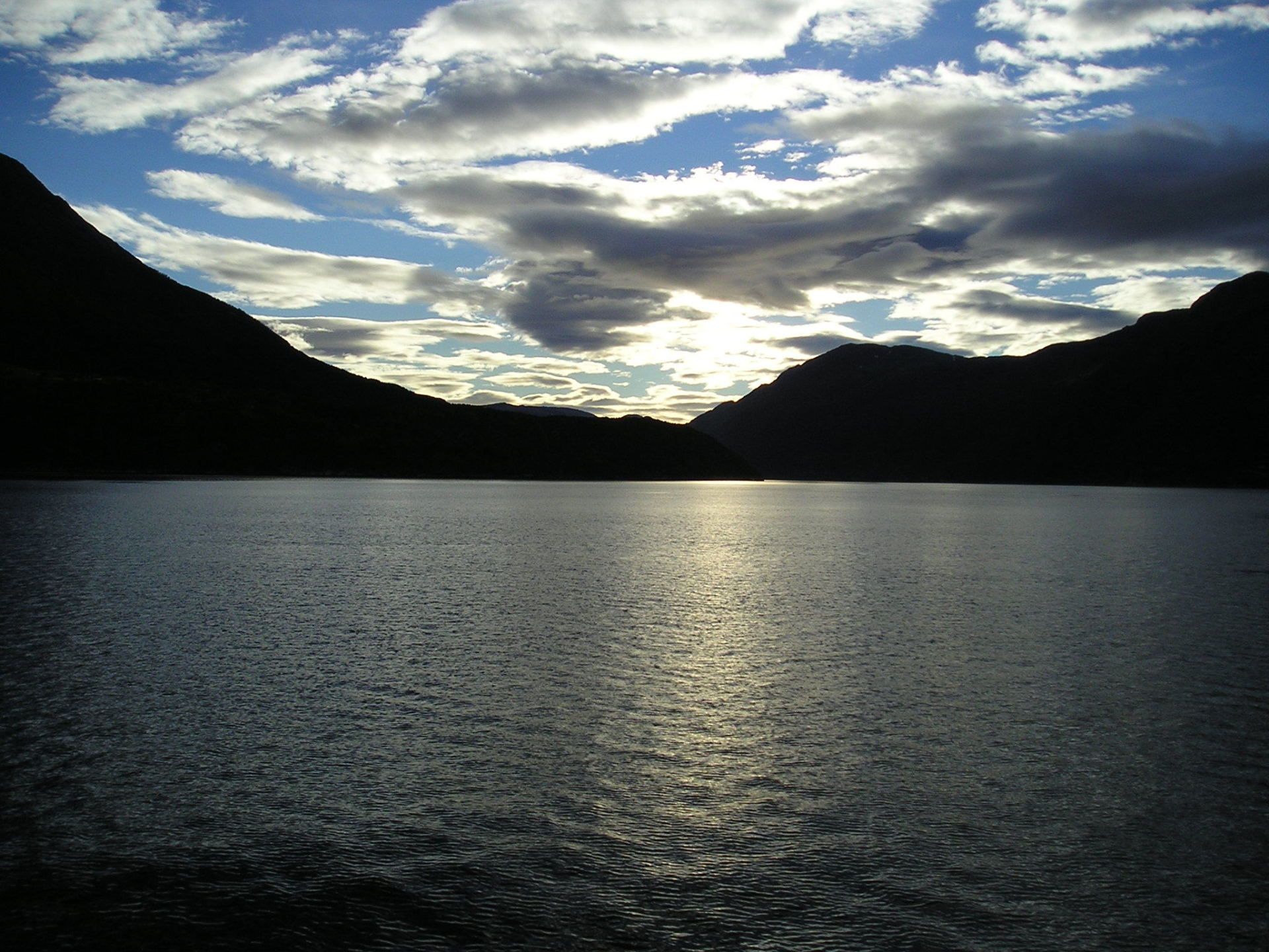 A lake with mountains in the background and clouds in the sky