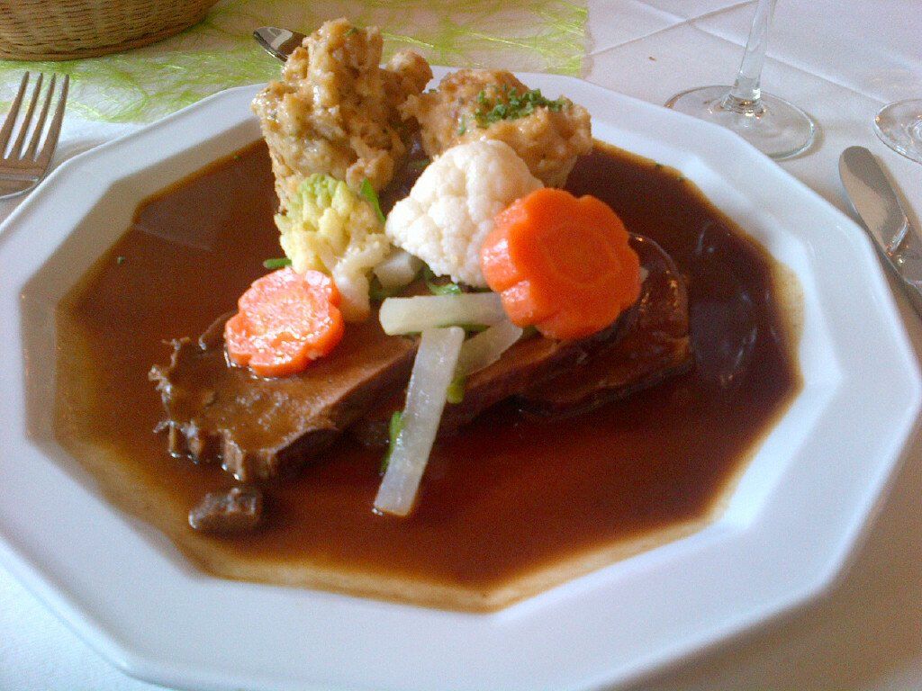 A white plate topped with meat and vegetables on a table