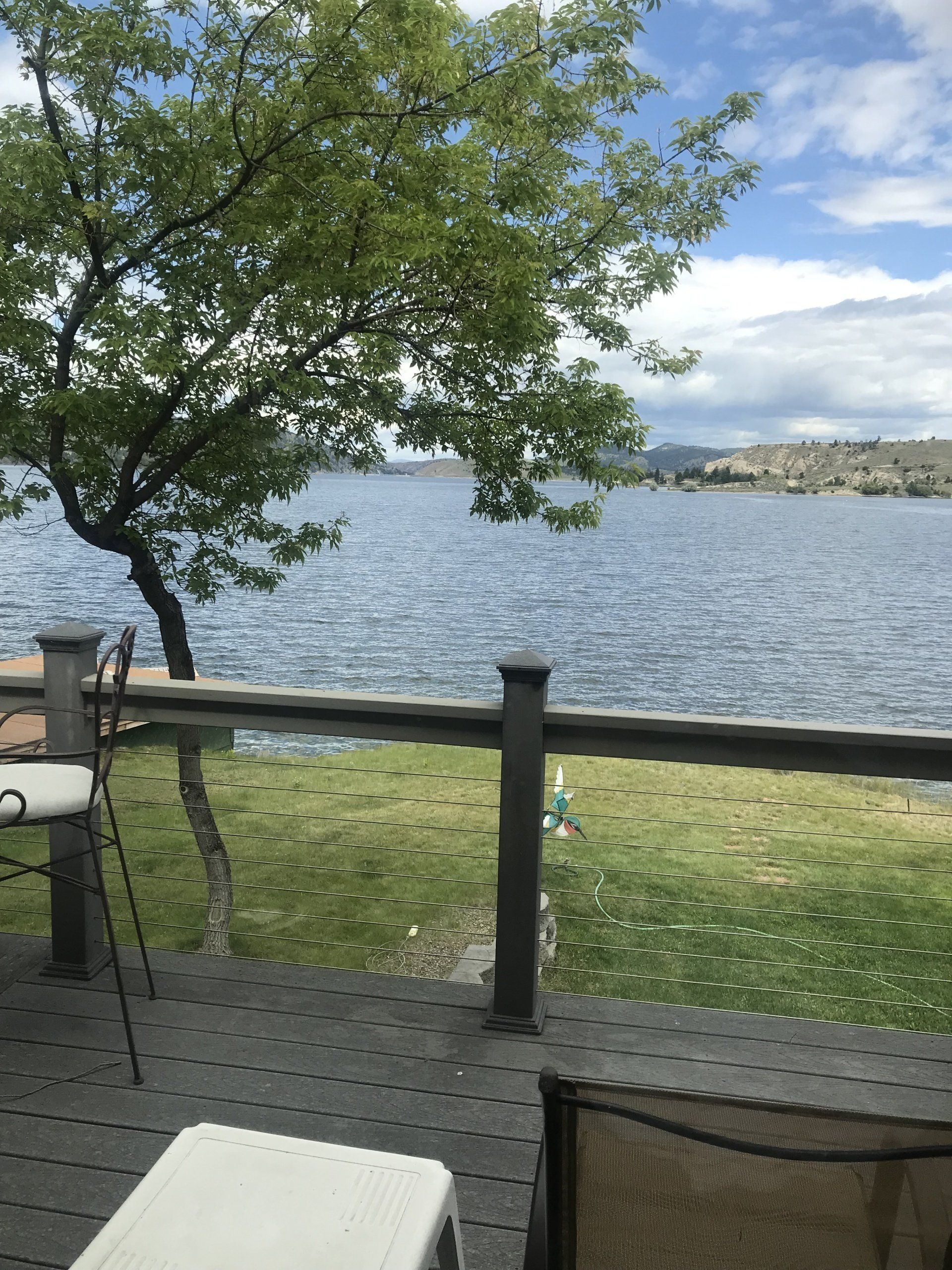 A view of a lake from a deck with chairs and a table