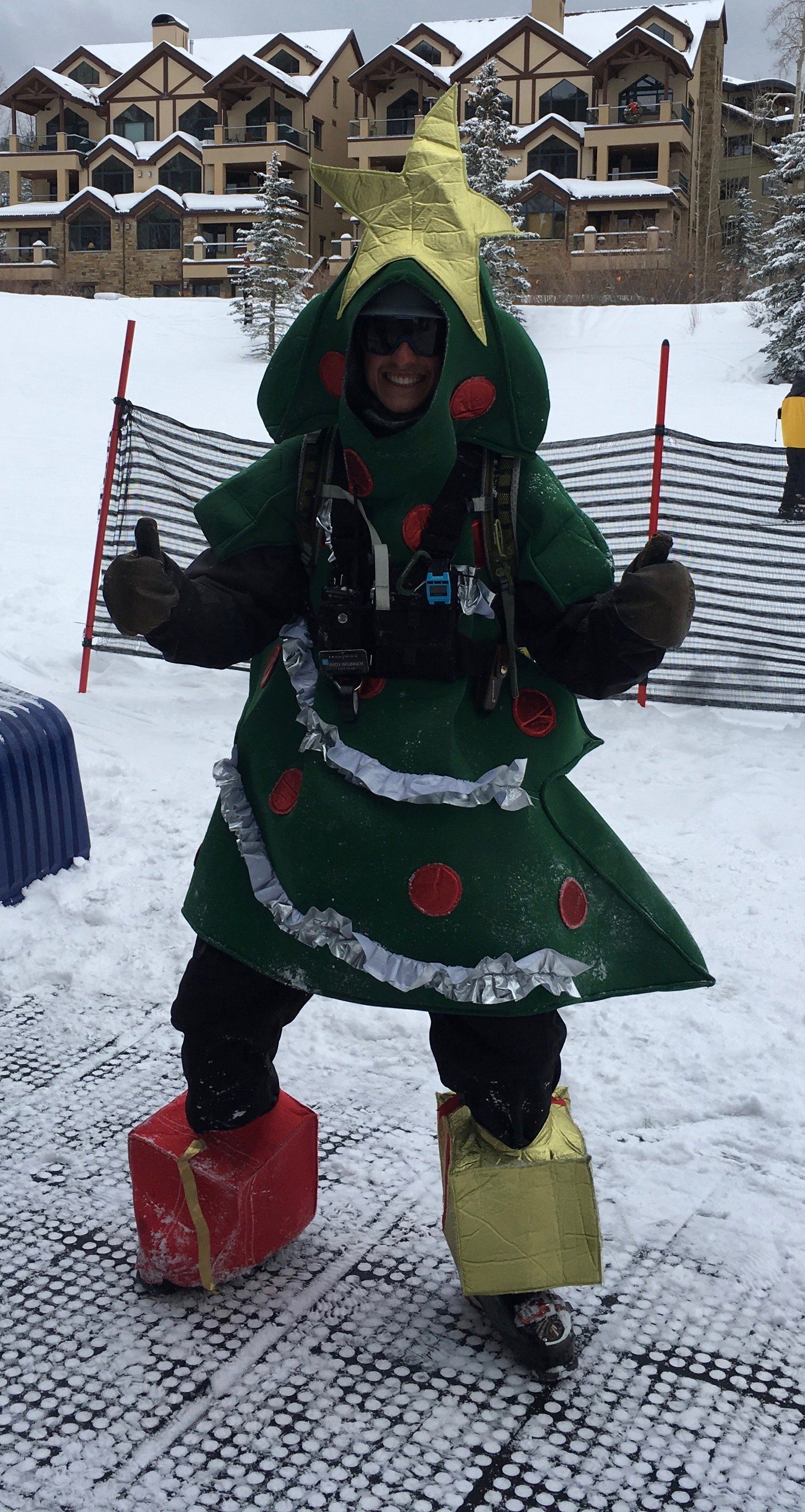 A person dressed as a christmas tree is standing in the snow