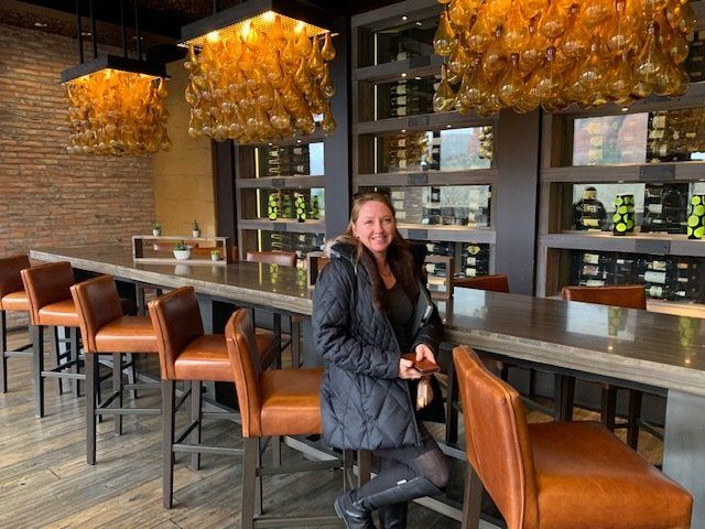 A woman is sitting at a long table in a restaurant.