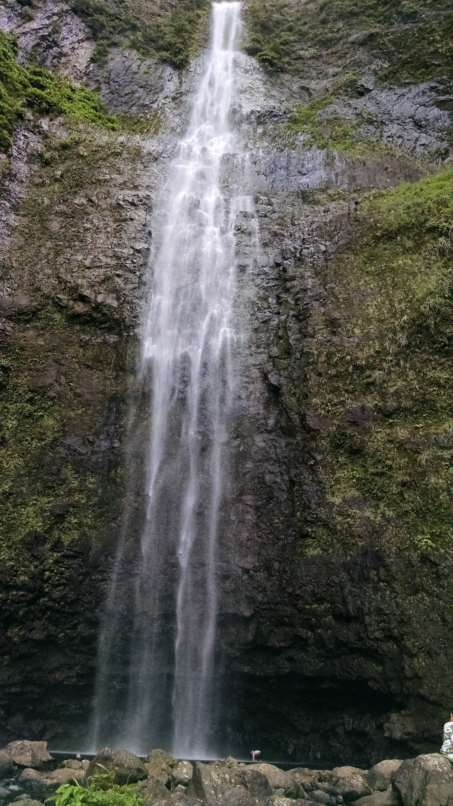 A waterfall is coming down a rocky cliff in the woods.