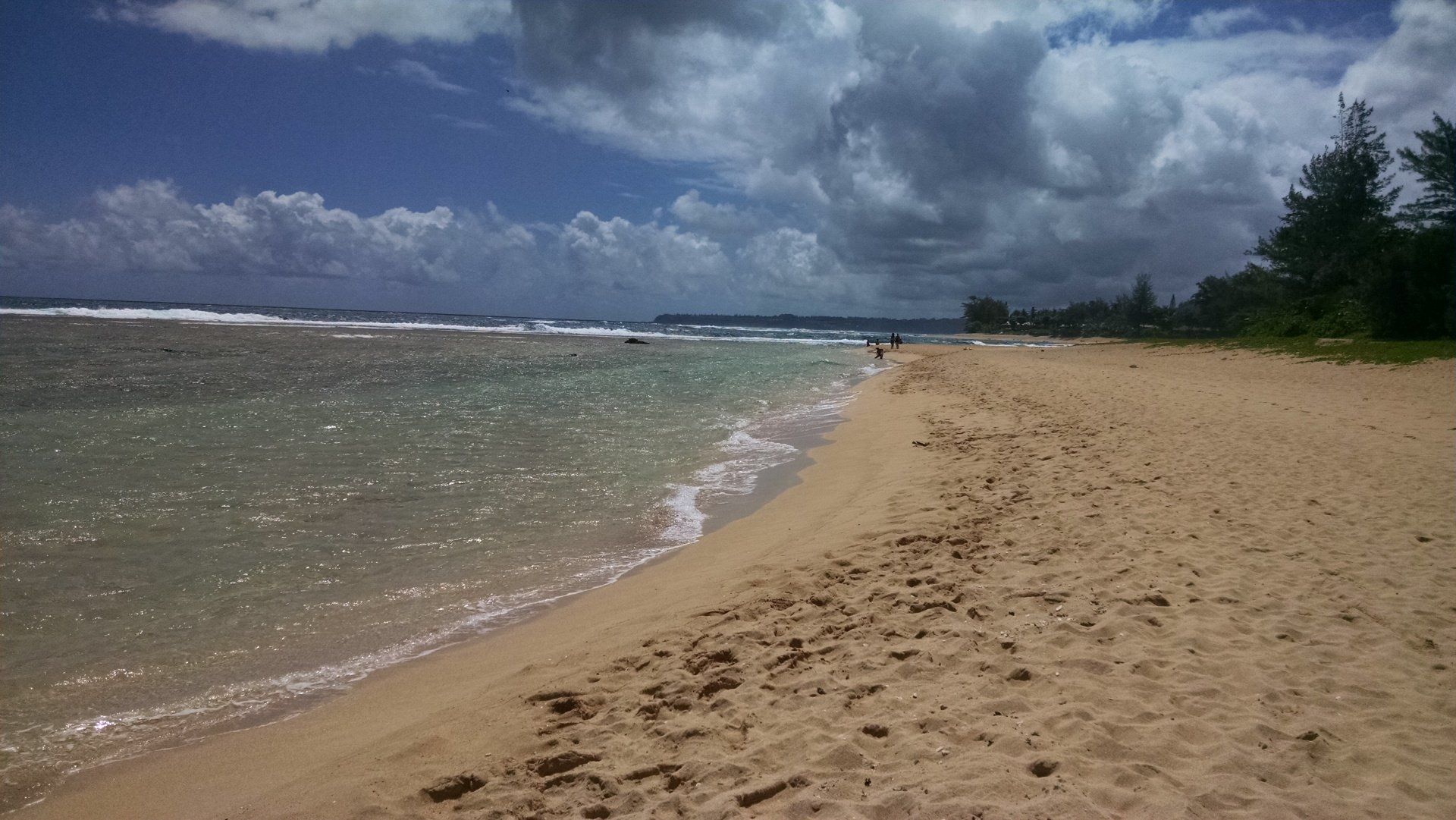 A sandy beach next to a body of water on a cloudy day.