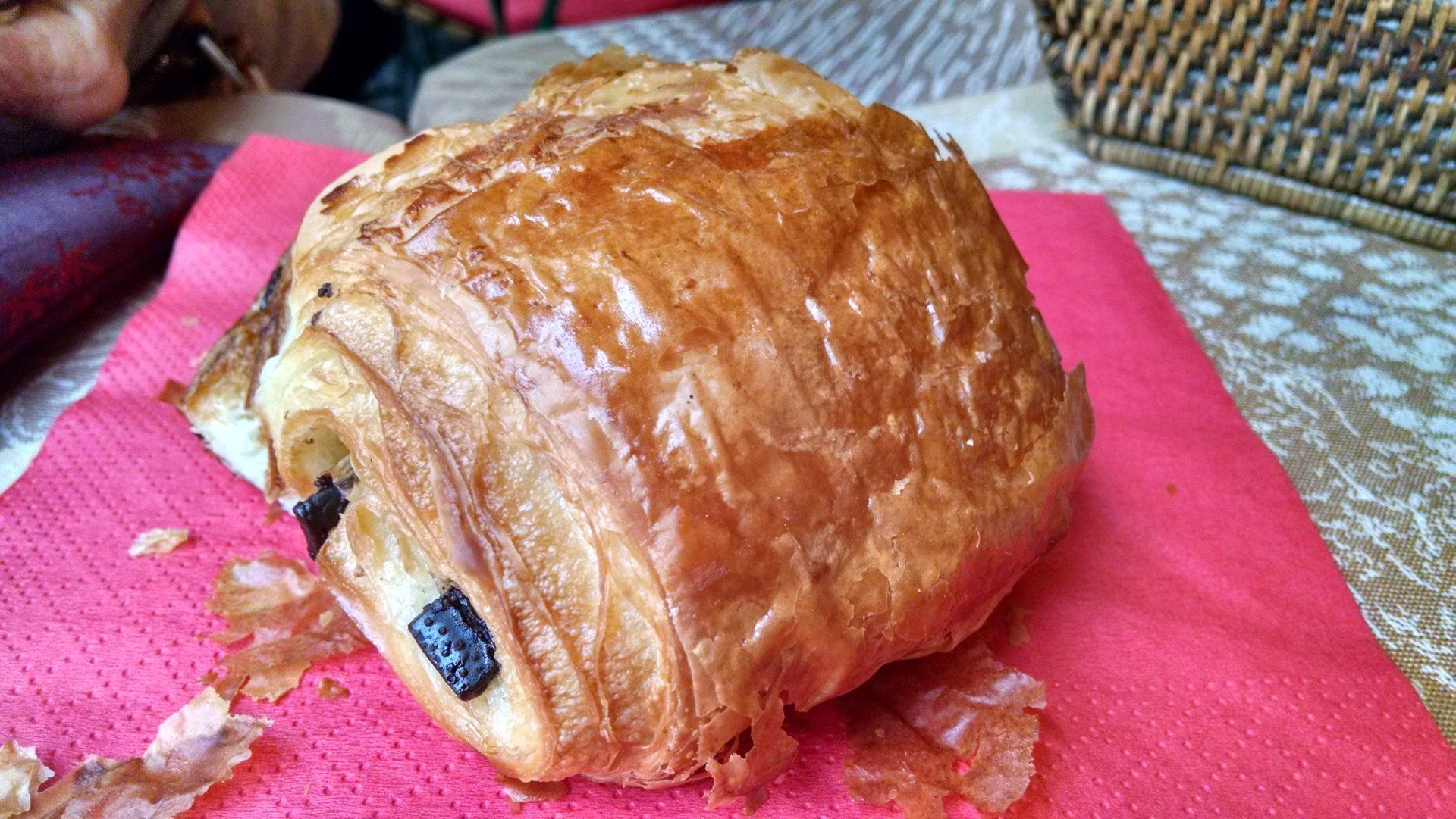 A close up of a chocolate croissant on a napkin on a table.