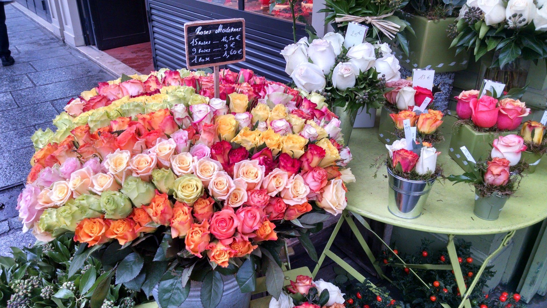 A bunch of flowers are sitting on a table in front of a flower shop.