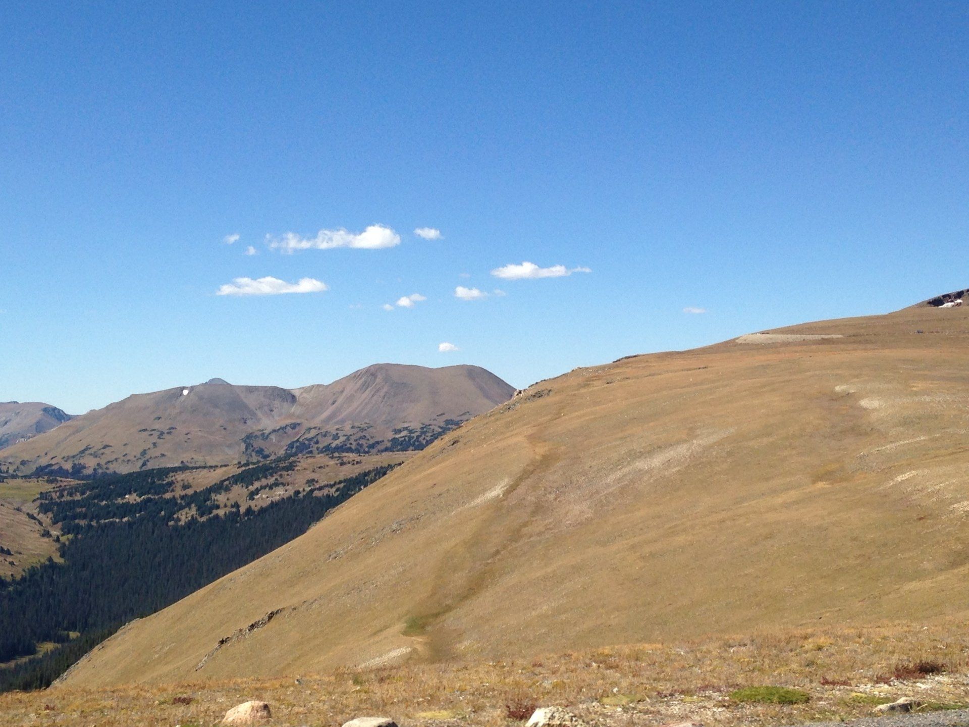 A mountain landscape with a blue sky and mountains in the background