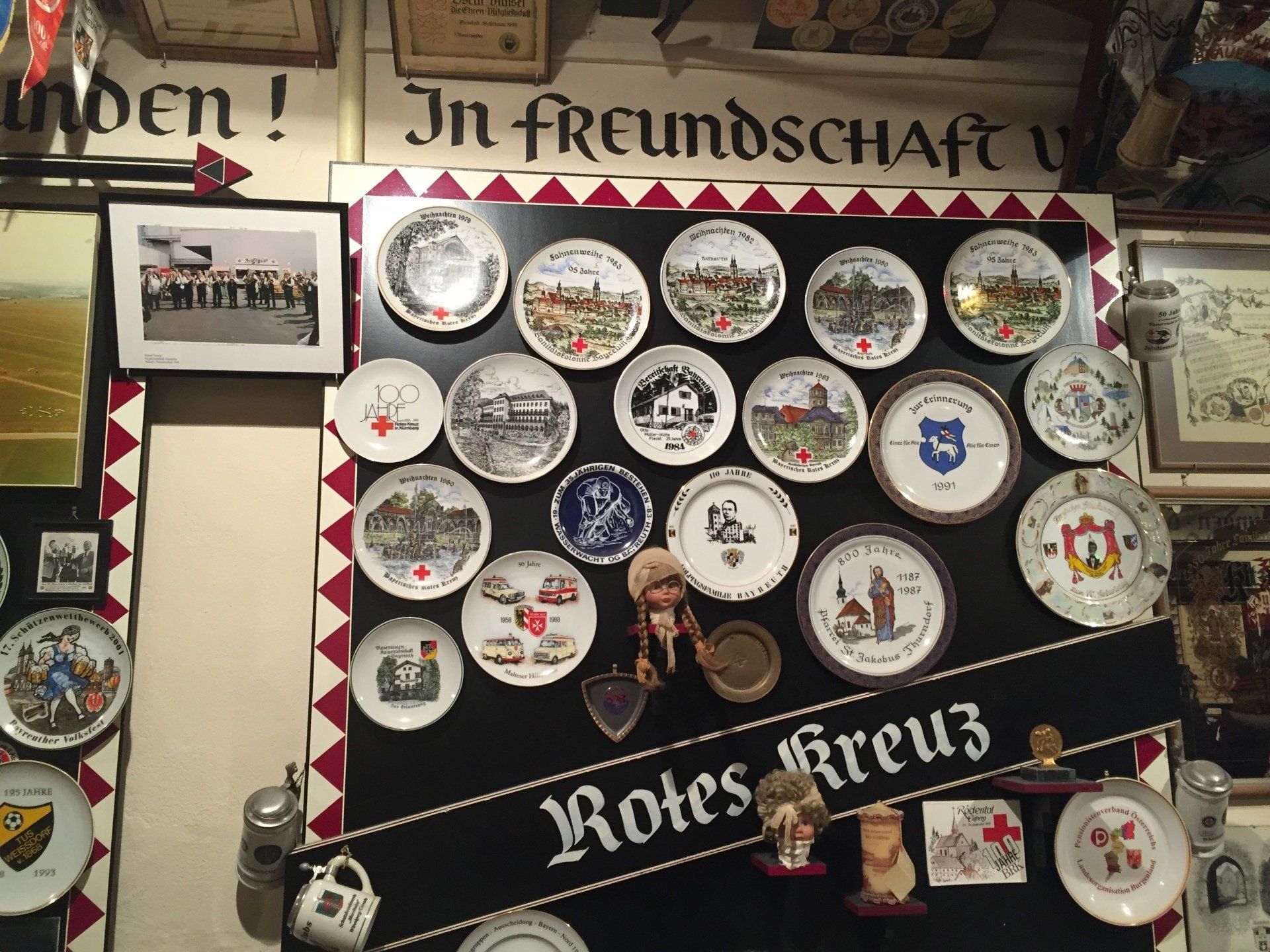 A wall with many plates and a sign that says 