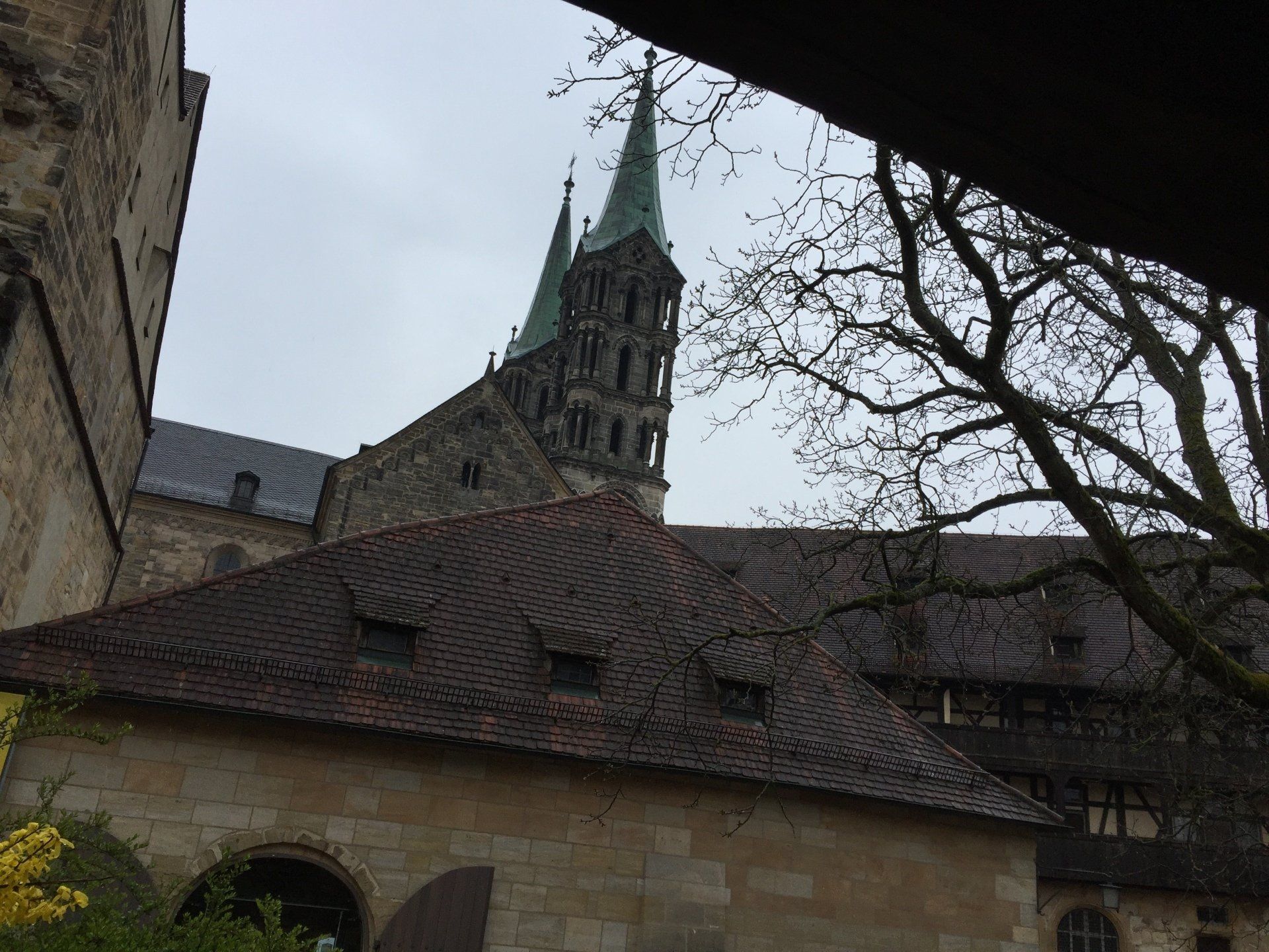 A church with a green steeple is behind a building