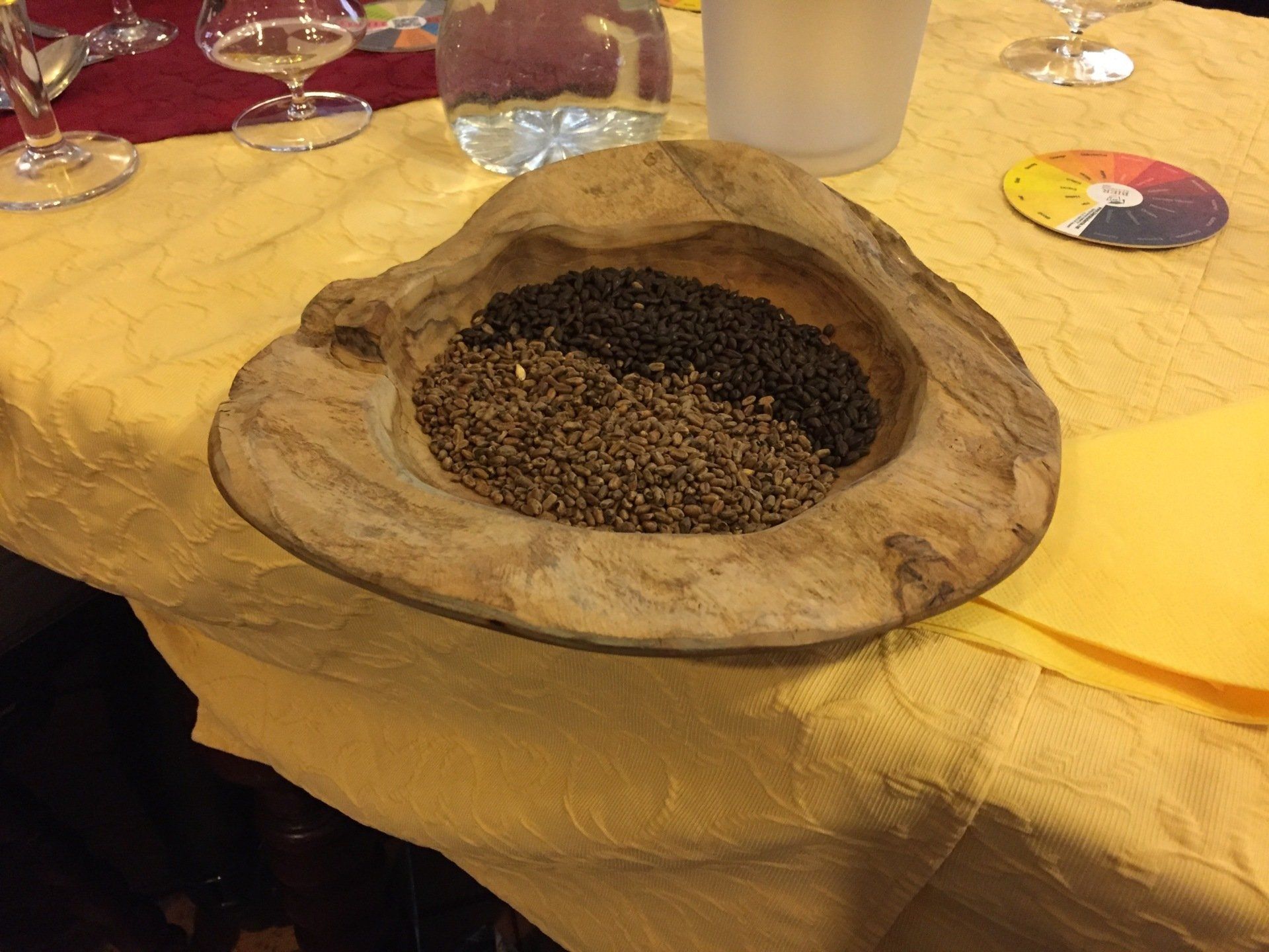 A wooden bowl filled with grains sits on a table.
