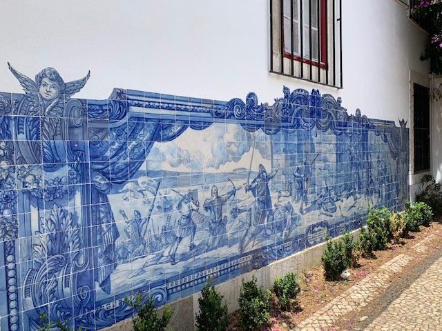 A blue and white tile mural on the side of a building.