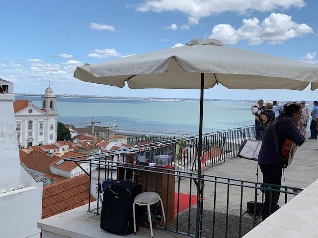 A man playing a guitar on a balcony overlooking the ocean