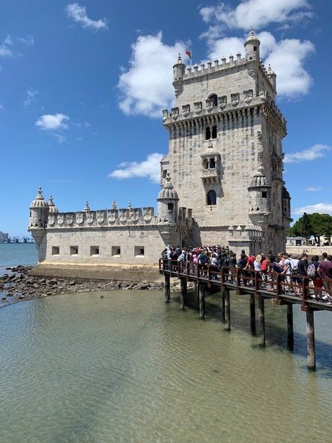 A group of people standing on a bridge in front of a castle