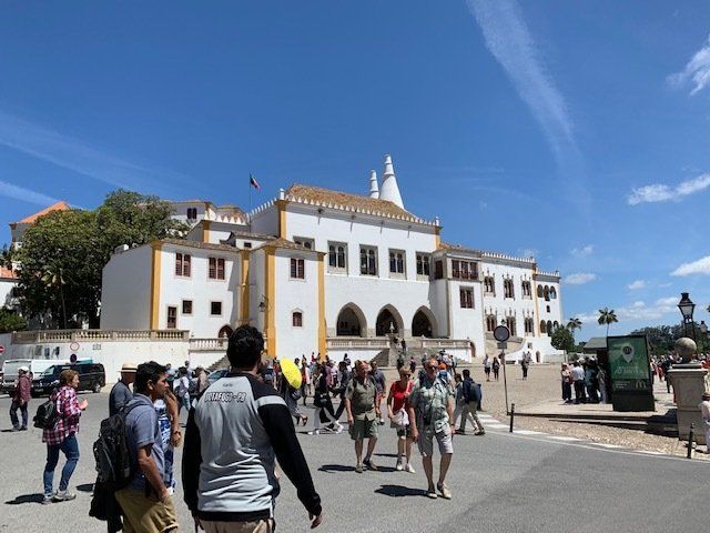 A group of people are walking in front of a large white building