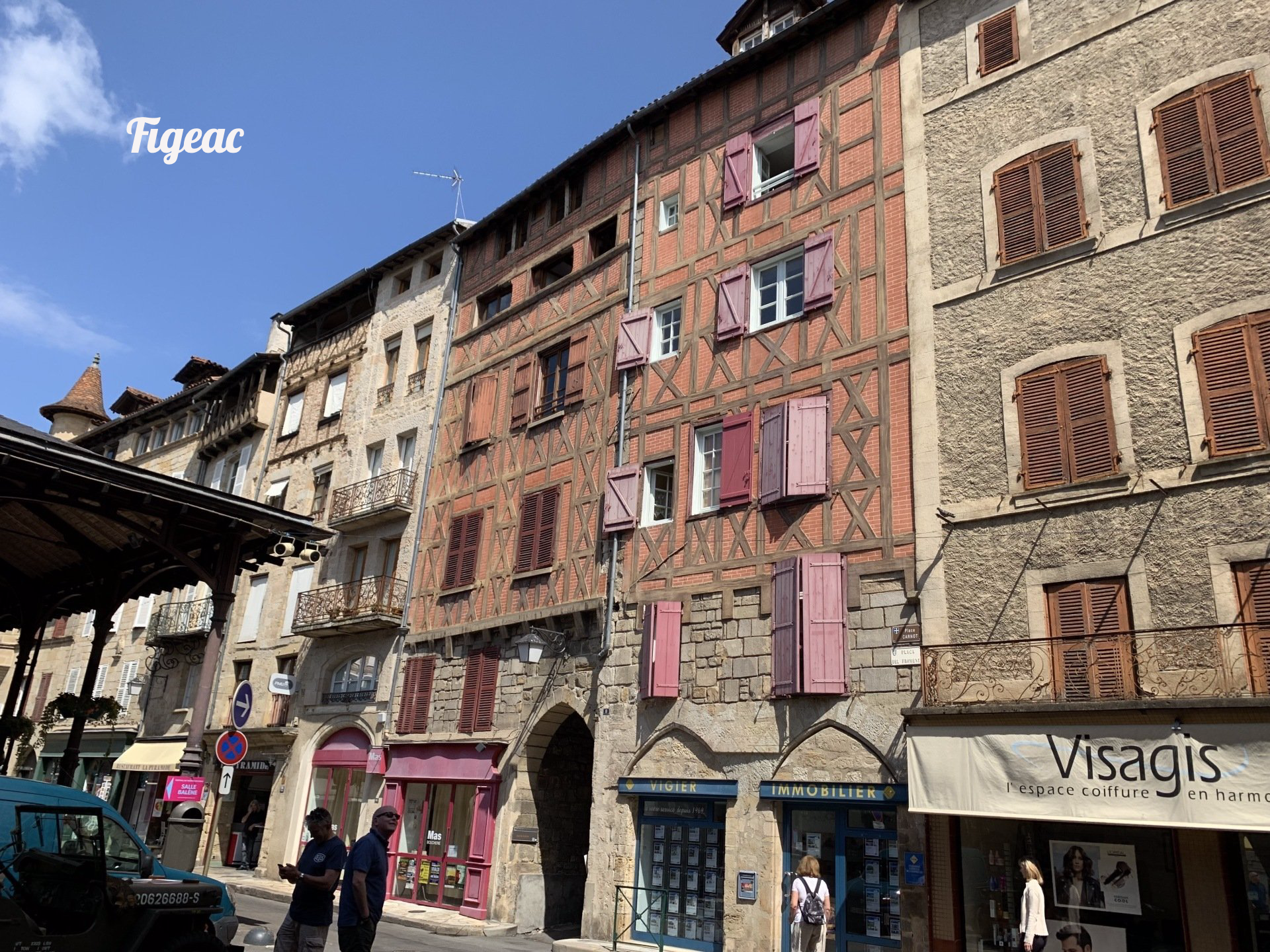 A group of people are walking down a street in front of a building.
