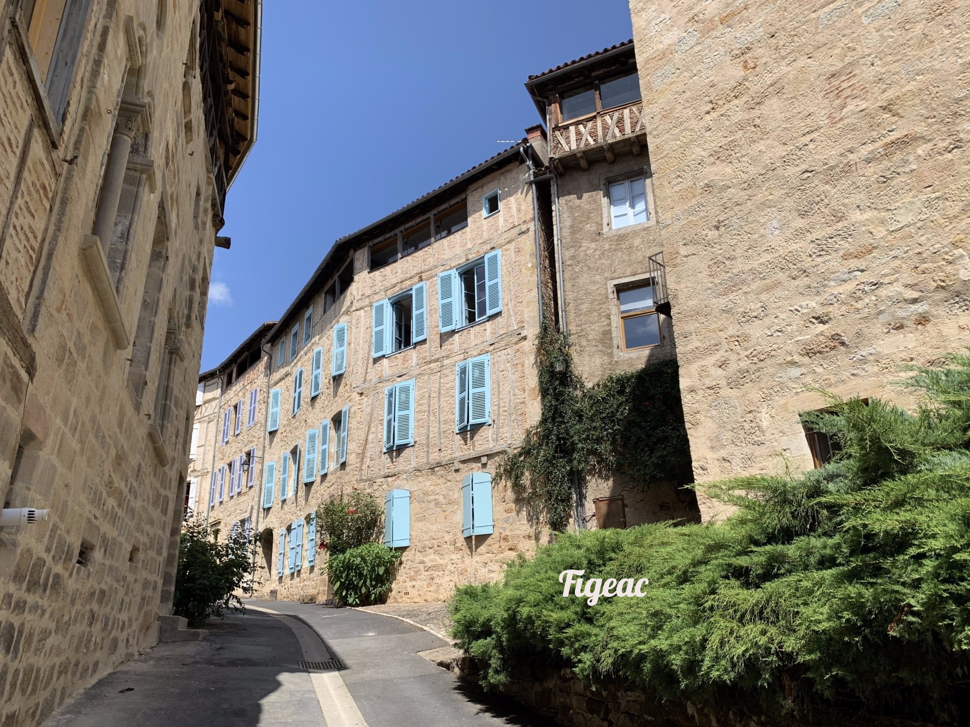 A narrow street between two buildings with blue shutters.