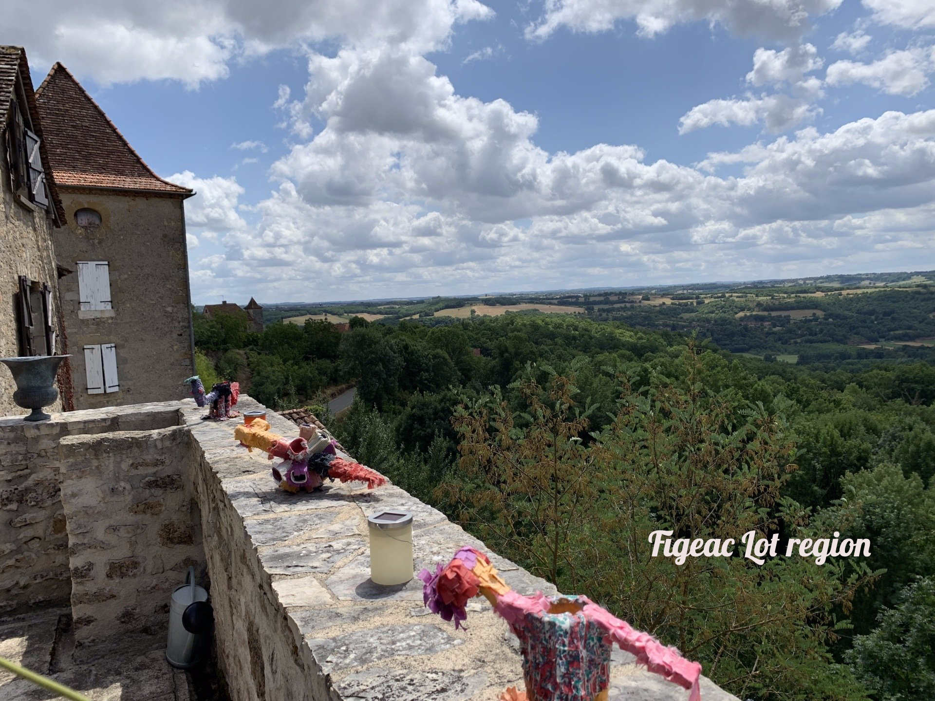 A stone wall with a view of a valley and a building in the background.
