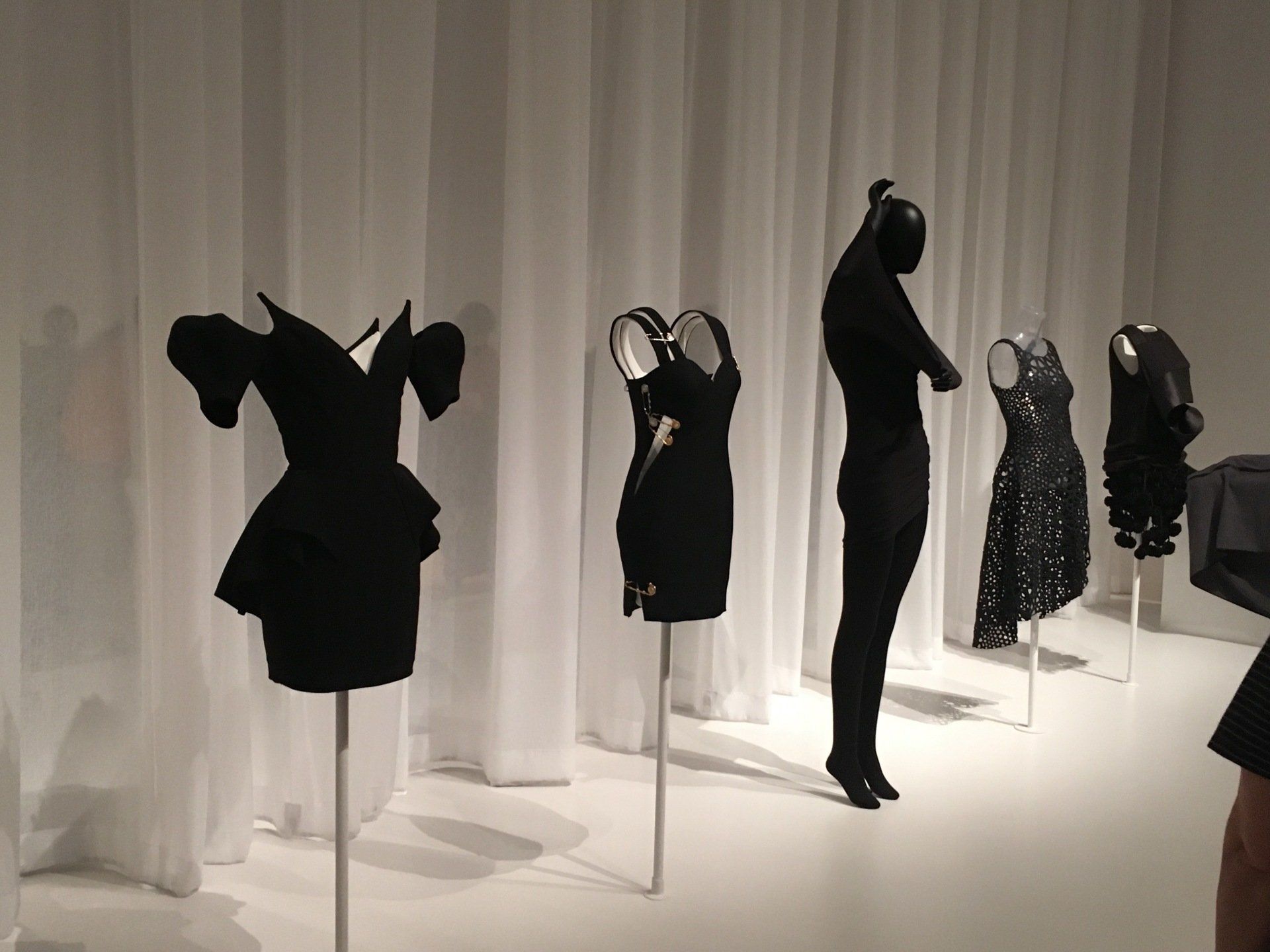 A row of black dresses are on display in a room