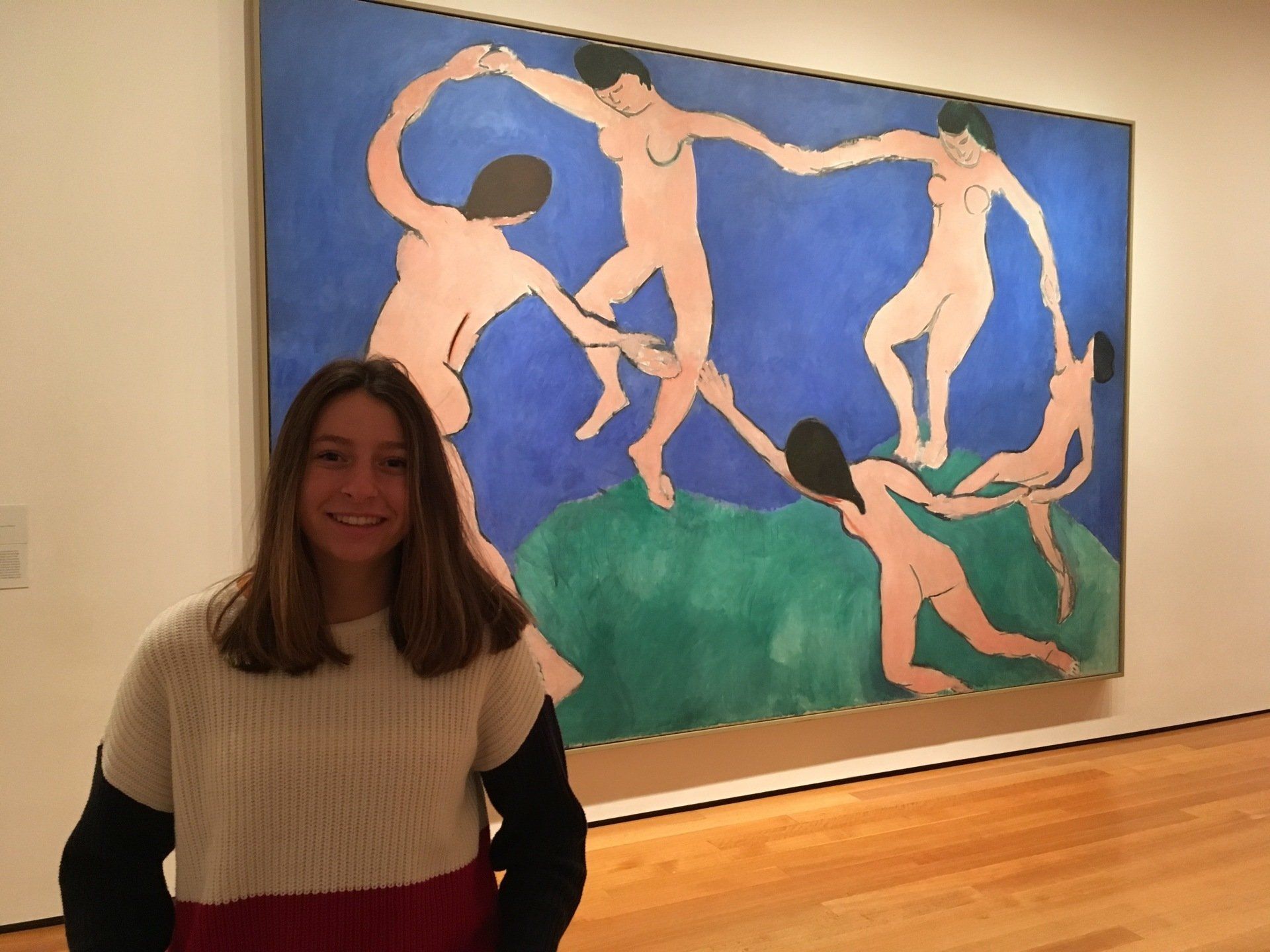 A standing woman with a painting behind her