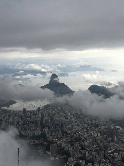 An aerial view of a city surrounded by mountains and clouds.